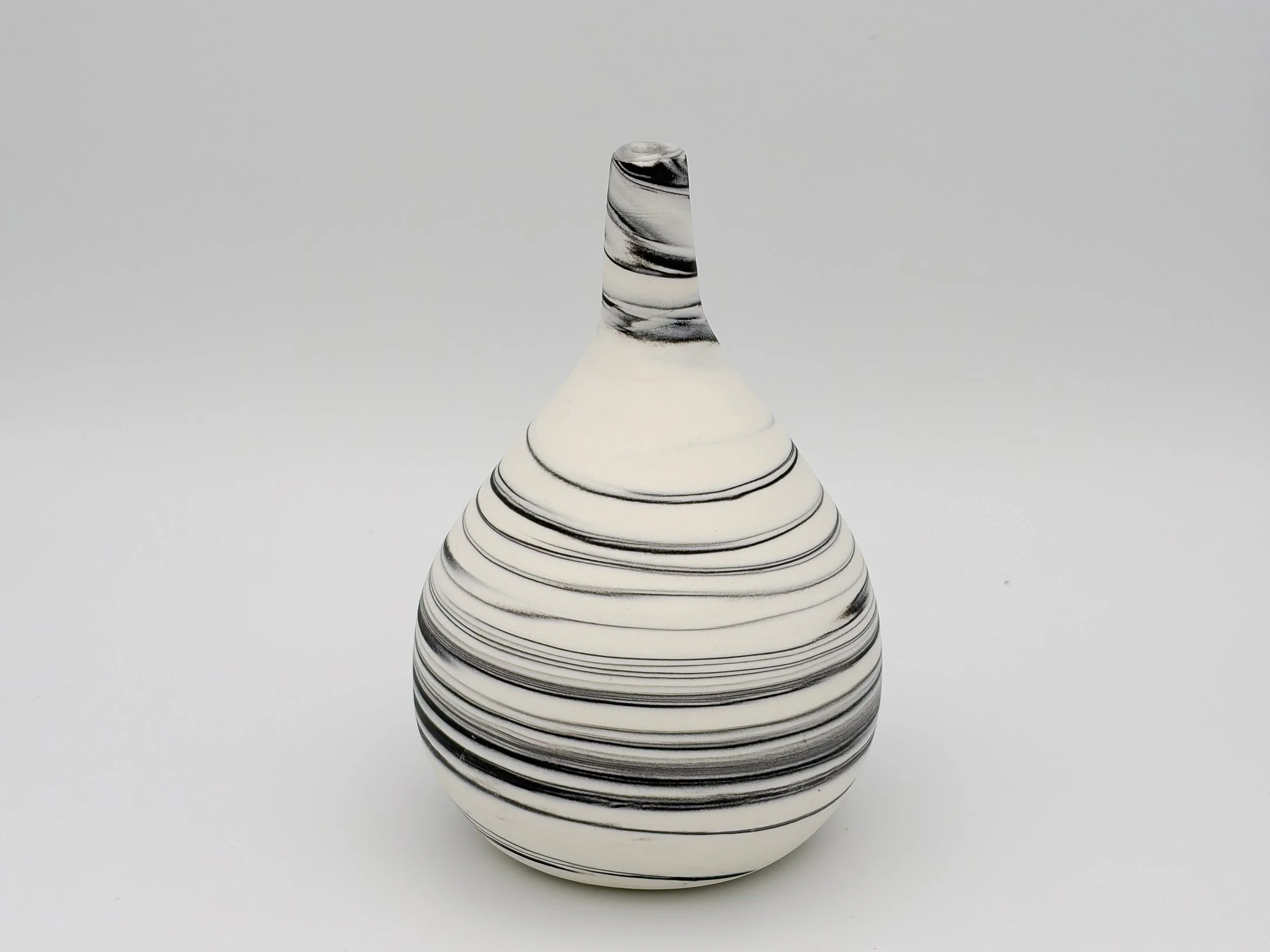 A black and white striped ceramic vase with a narrow neck and wide base, set against a plain white background.