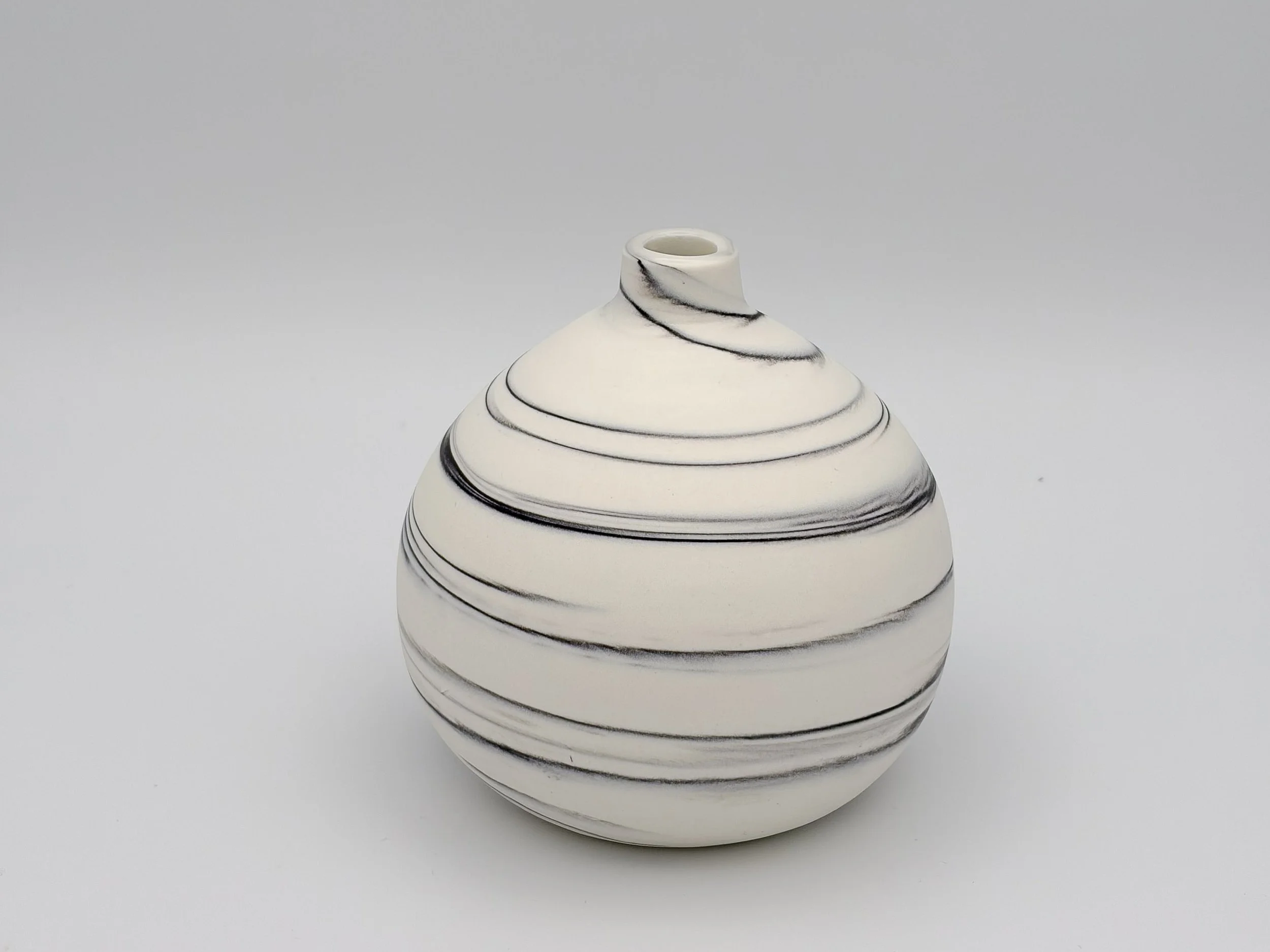 White ceramic vase with black swirling lines, rounded base, tapering to a smaller opening at the top, against a plain light gray background.