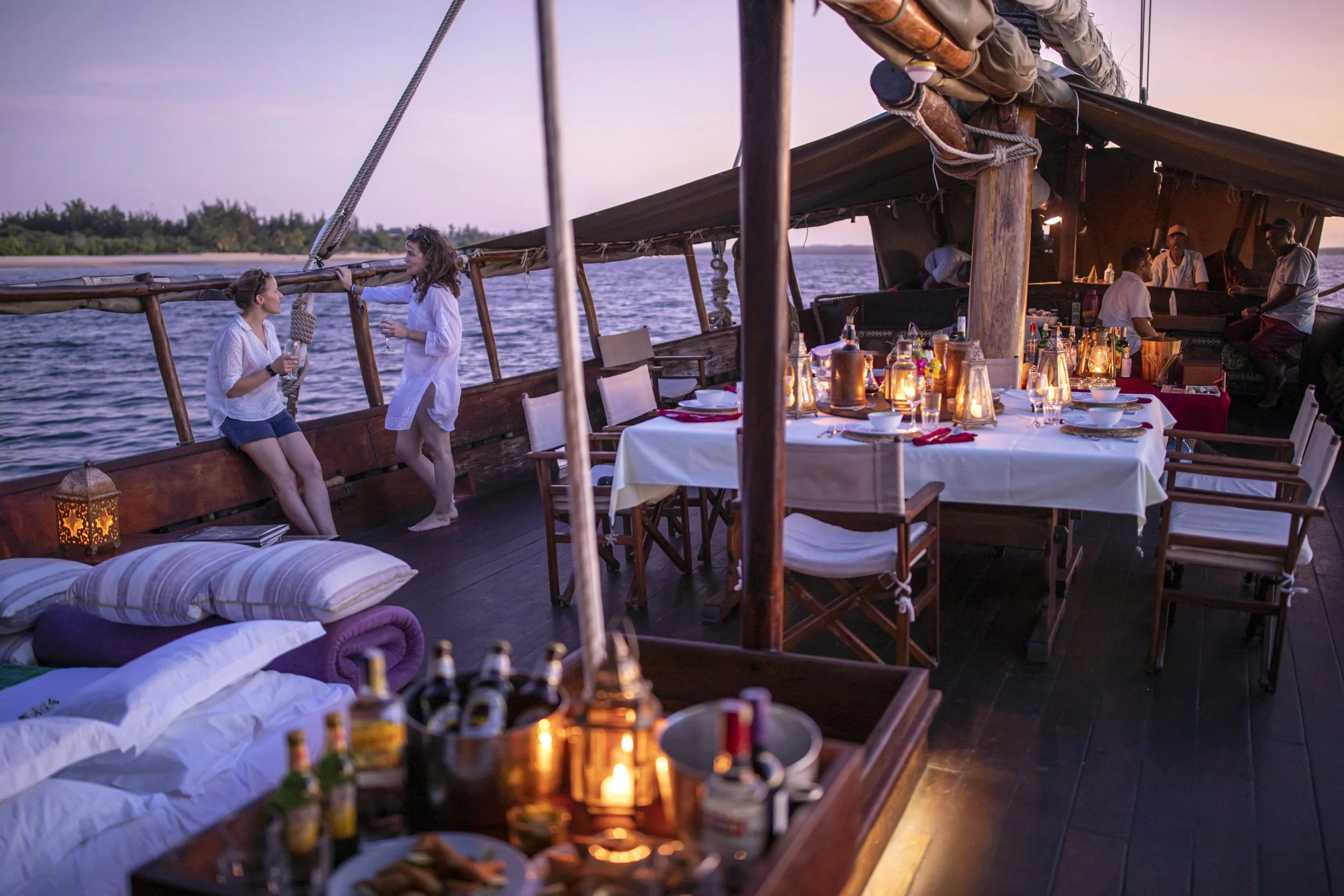Open-air dining and lounge aboard the Tusitiri dhow in Lamu, Kenya, where guests spend the night sailing the tranquil waters of the Swahili Coast.