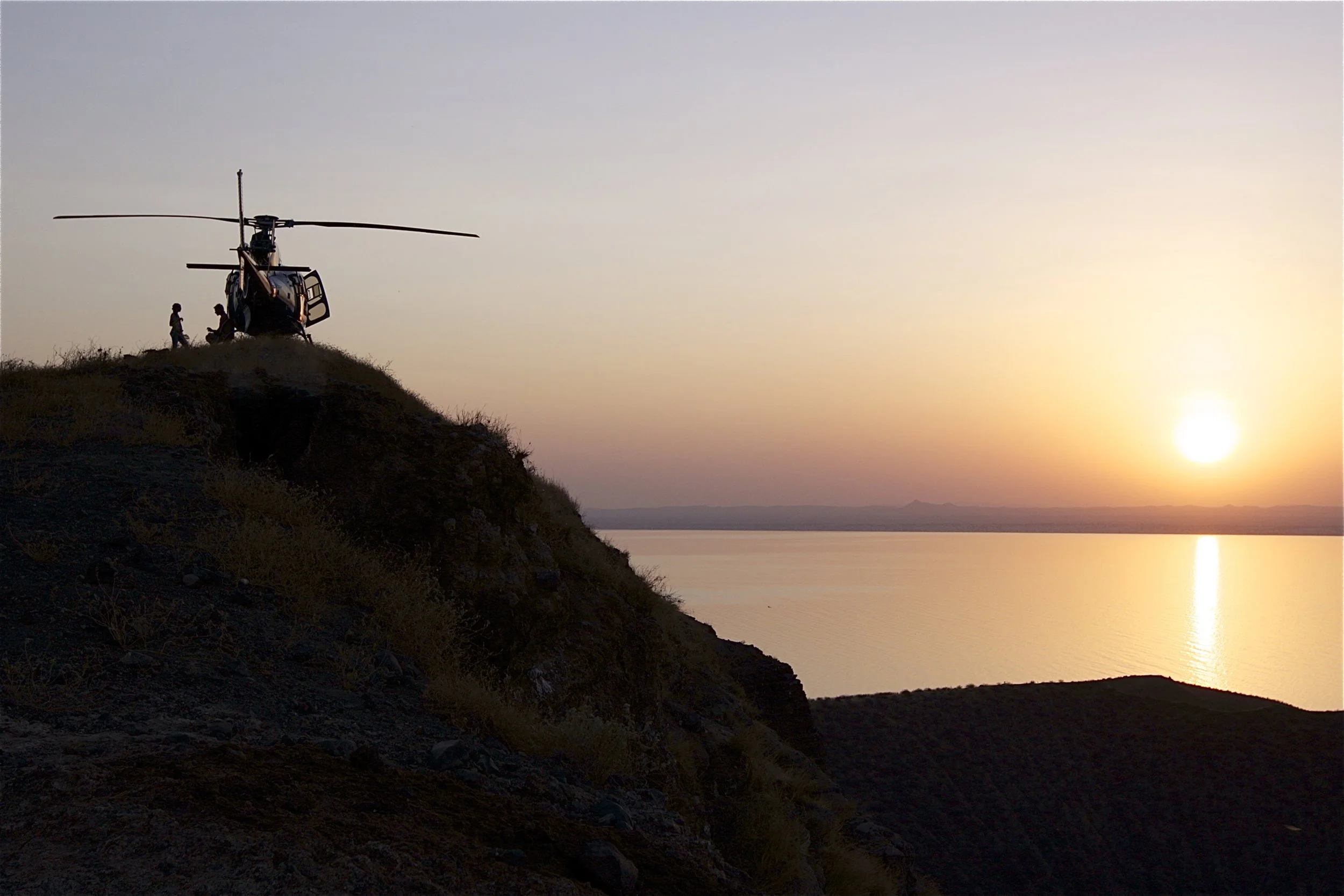 Sunset sundowners overlooking Lake Turkana during a helicopter safari in northern Kenya, revealing the remote landscapes of East Africa's Northern Frontier.