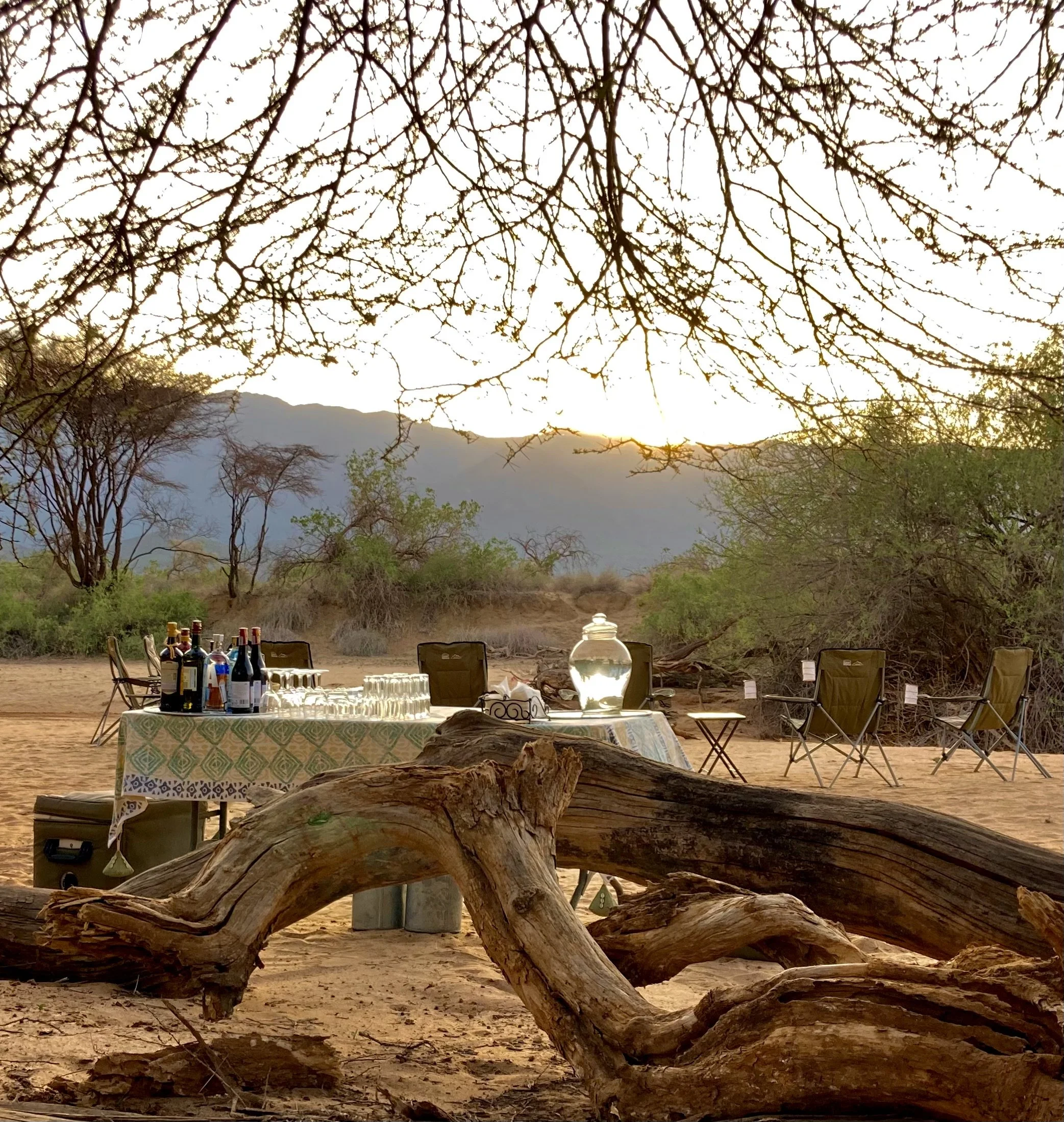 Open-air sundowner bush bar at Koros Camp in northern Kenya, offering a remote luxury safari experience as the sun sets over the surrounding wilderness