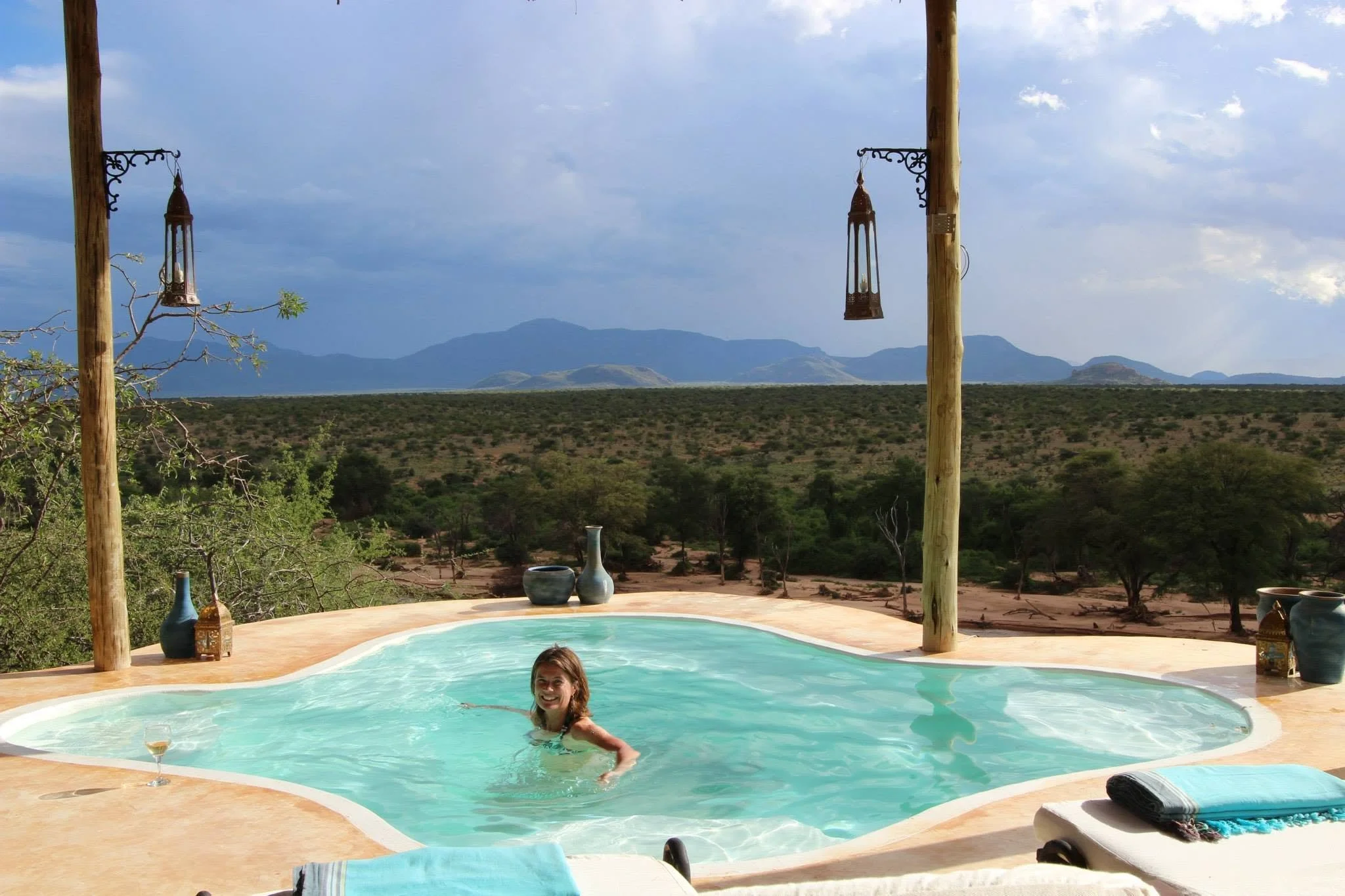 Solo female traveller enjoying the infinity pool at Sasaab Lodge in Samburu, Kenya, overlooking the Ewaso Nyiro River during a luxury safari in the Westgate Conservancy and enjoyinhg the view back to the Laikipia Plateau