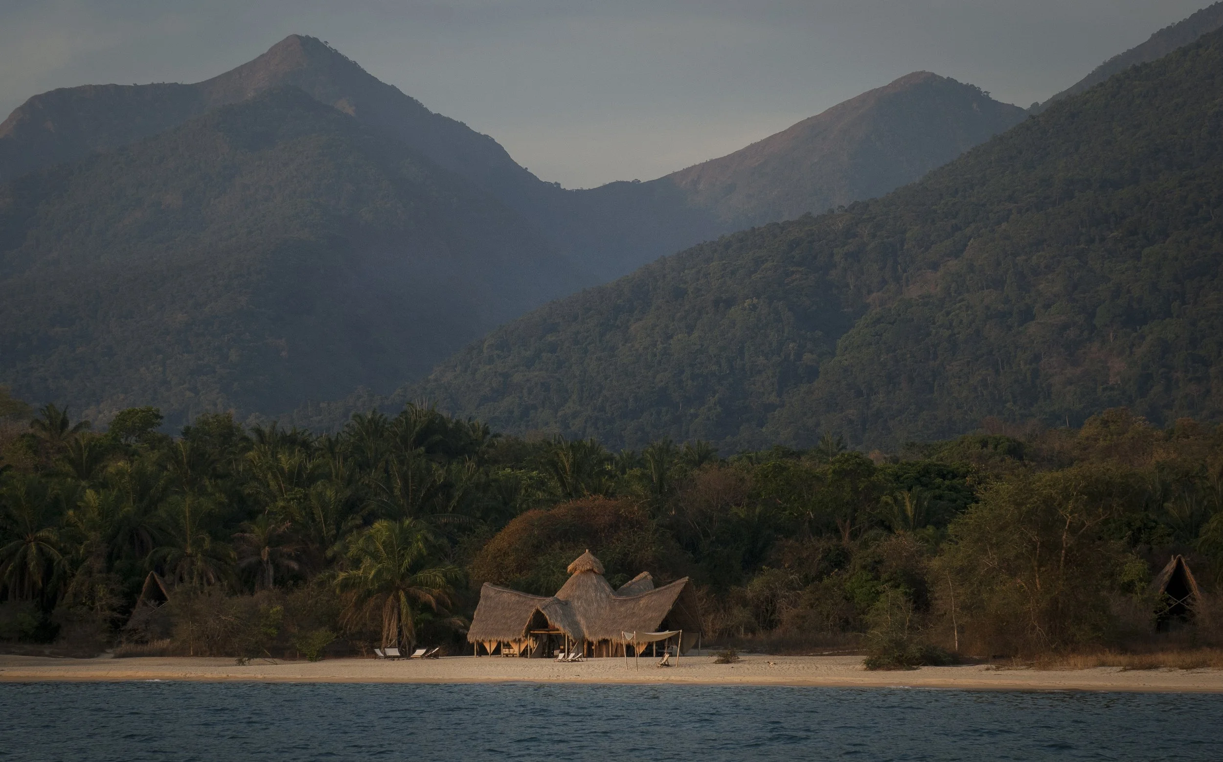 View of Greystoke Mahale on the shores of Lake Tanganyika and the Mahale Mountains National Park, Tanzania, in background where guests trek through the forest to observe wild chimpanzees in their natural habitat.
