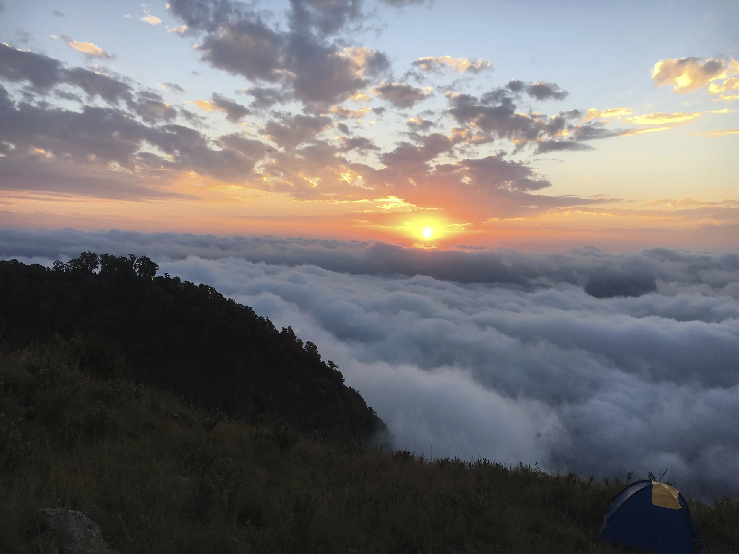Remote wilderness camp in the Matthews Range, northern Kenya, overlooking a sea of clouds at sunrise during a multi-day walking safari