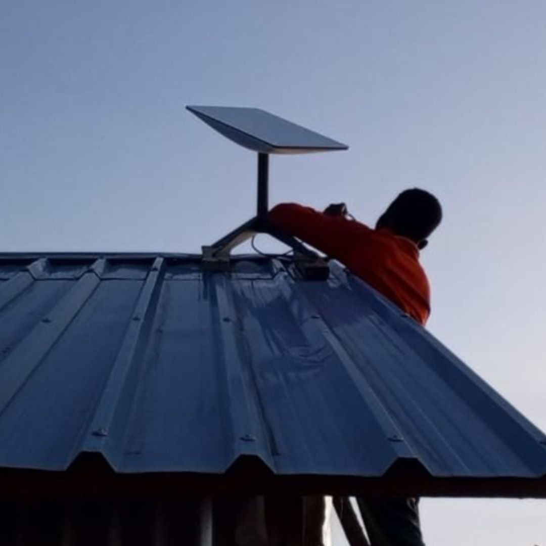 Un instalador coloca una antena parabólica de Starlink en una azotea para ampliar el acceso sostenible a internet y conectar a comunidades desfavorecidas a través de la misión de inclusión digital de unconnected.org.