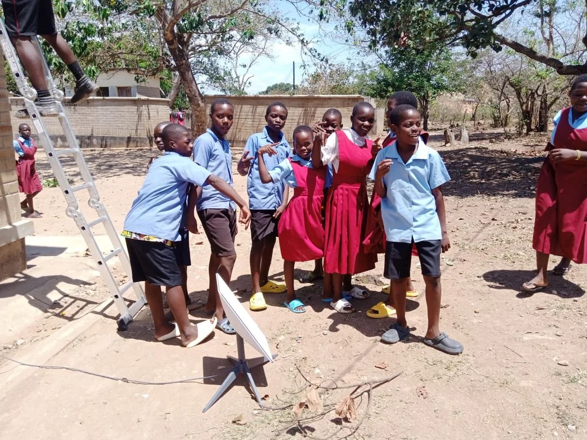 Niños de pie frente a un edificio comunitario rural, lo que representa la necesidad de un acceso a internet fiable y asequible, mientras unconnected.org trabaja para cerrar la brecha digital en regiones desatendidas de todo el mundo.