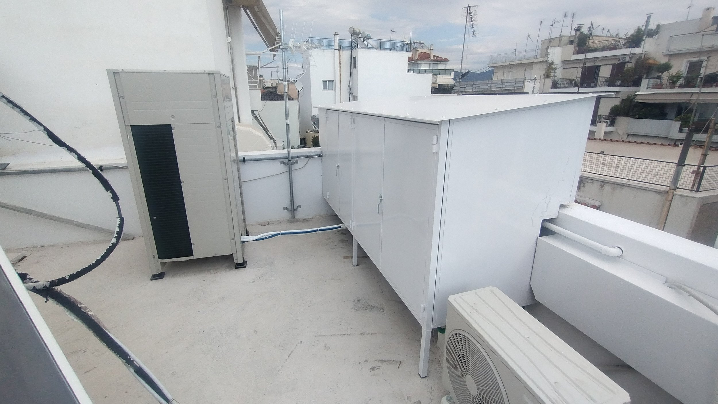 Rooftop with HVAC units and electrical equipment, in an urban residential area.
