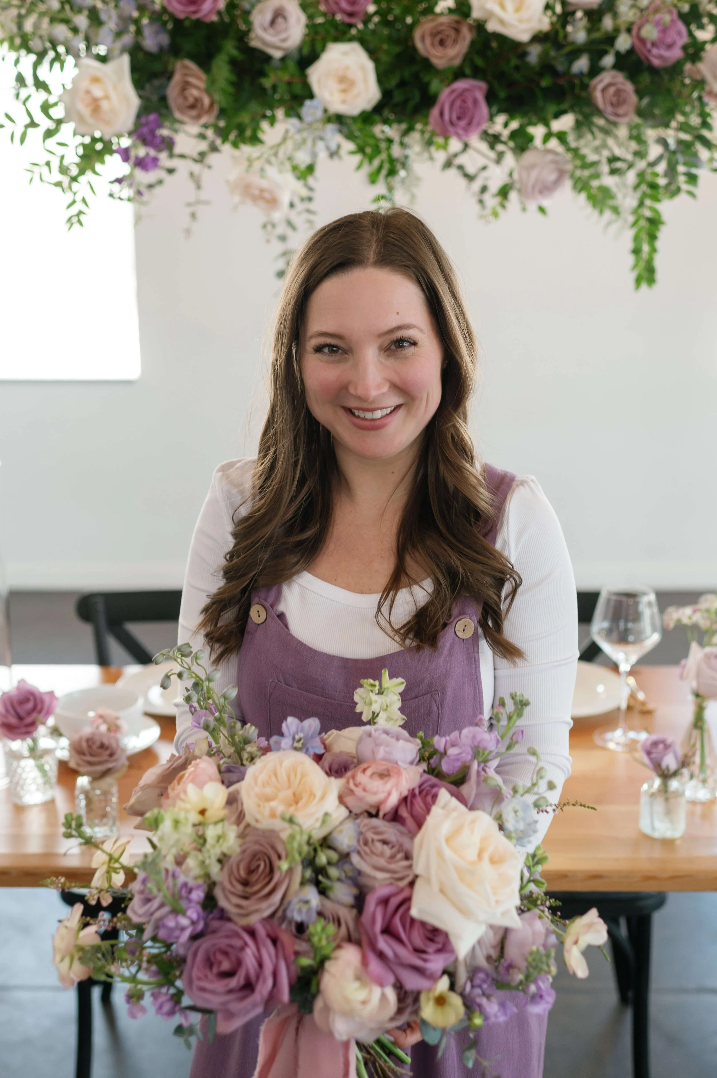 Beth, the floral designer at For Floral Sake, smiling at the camera while holding a lush bouquet.