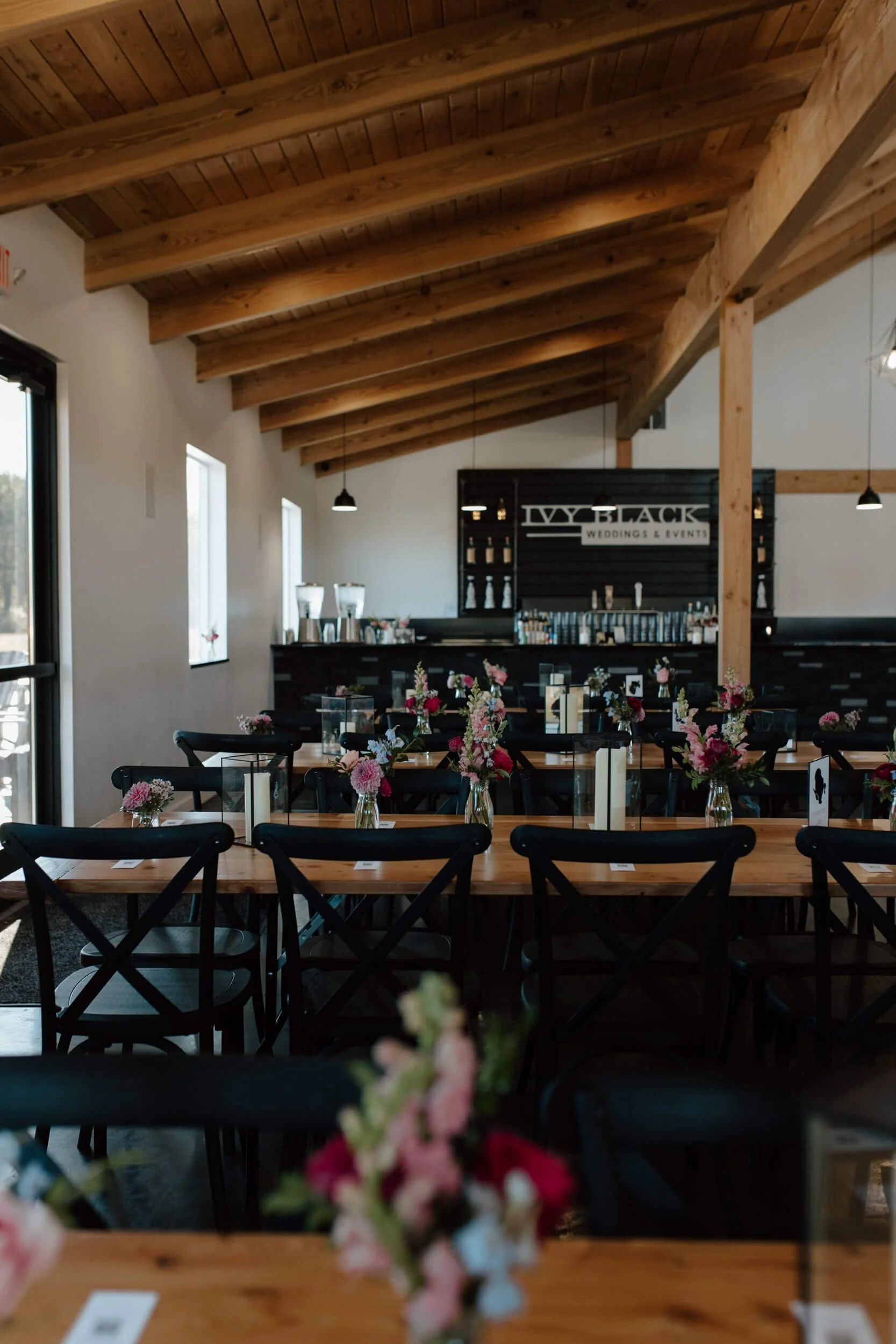 Reception tables with colorful bud vases inside Ivy Black wedding venue in Duluth, Minnesota.