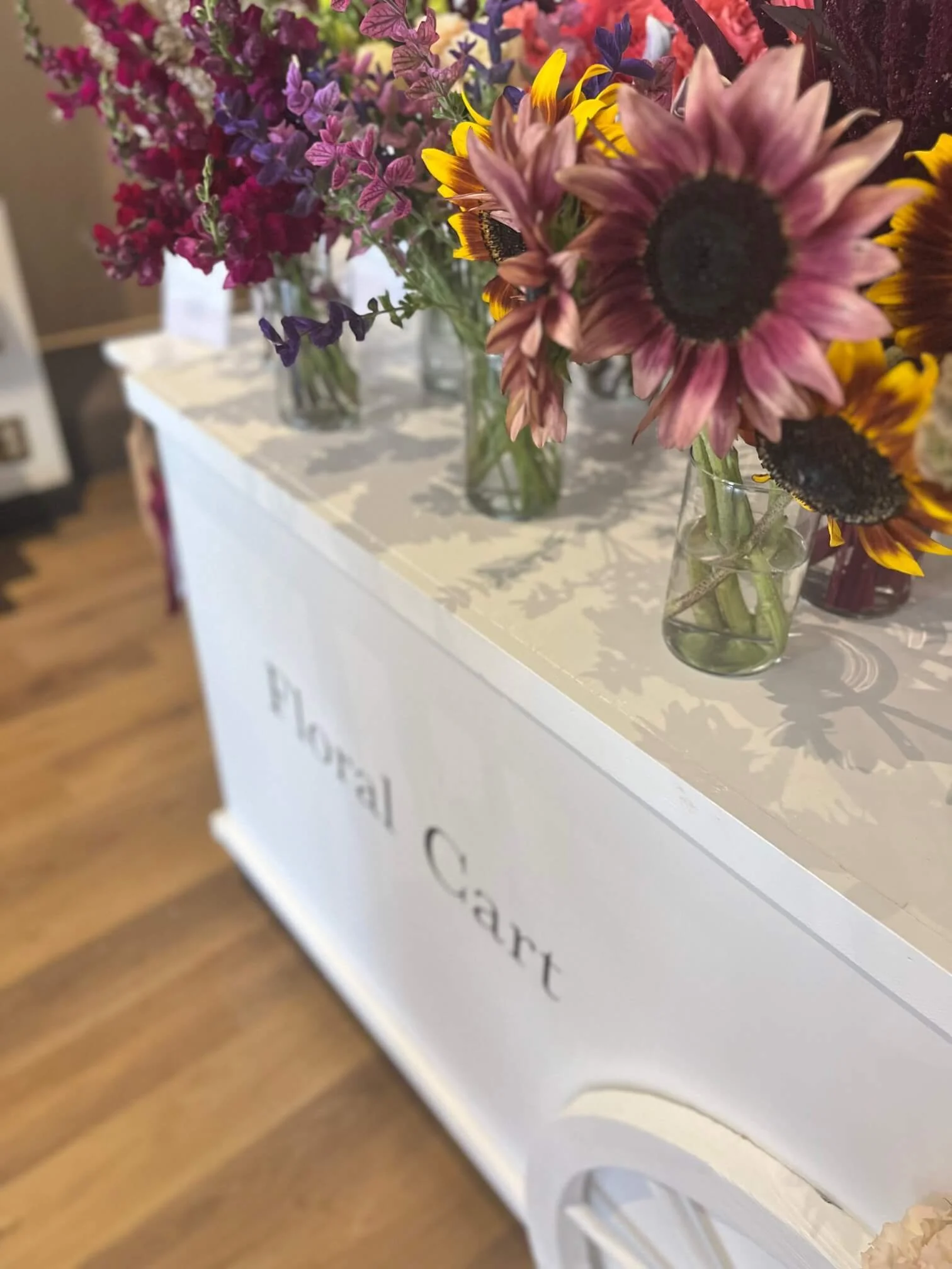 Close-up of a floral cart filled with late summer blooms in bold, seasonal colors.
