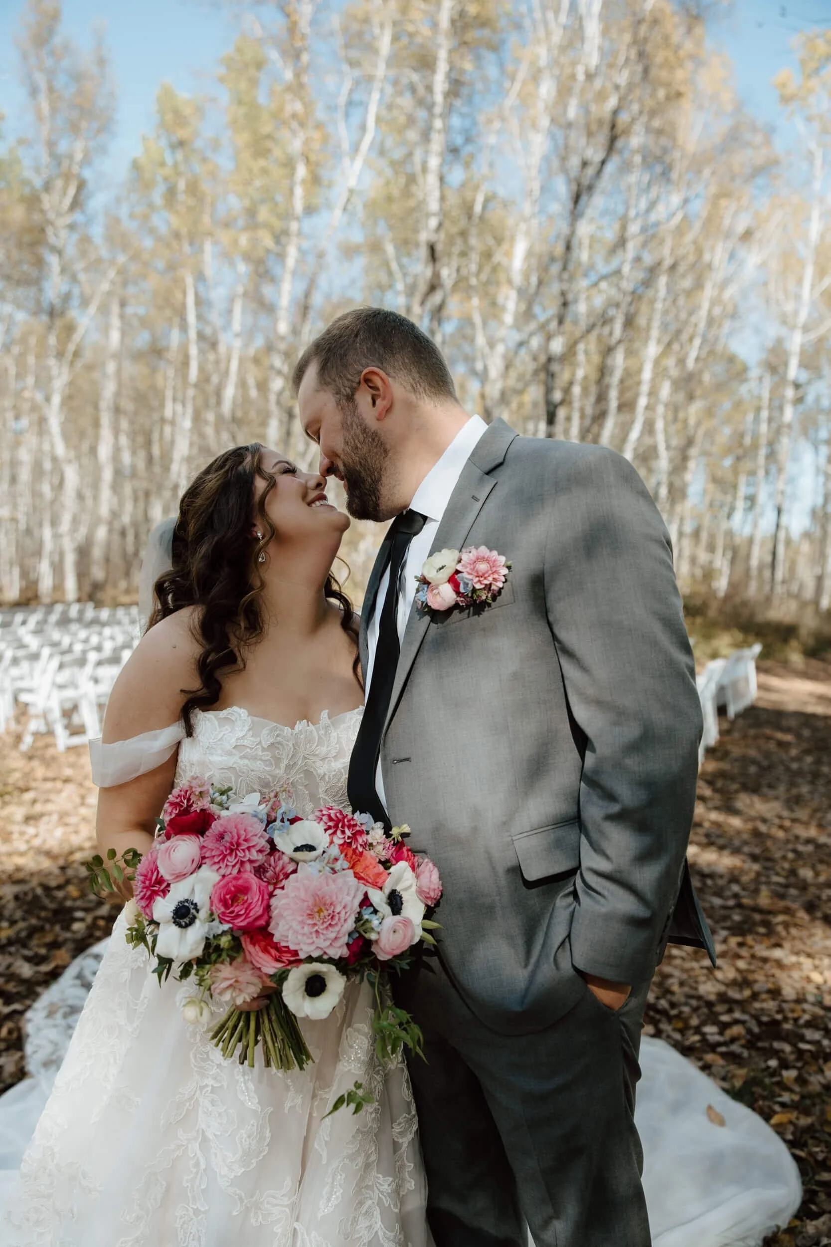 Bride and groom about to kiss in the fall woods while holding a colorful bridal bouquet at Ivy Black.