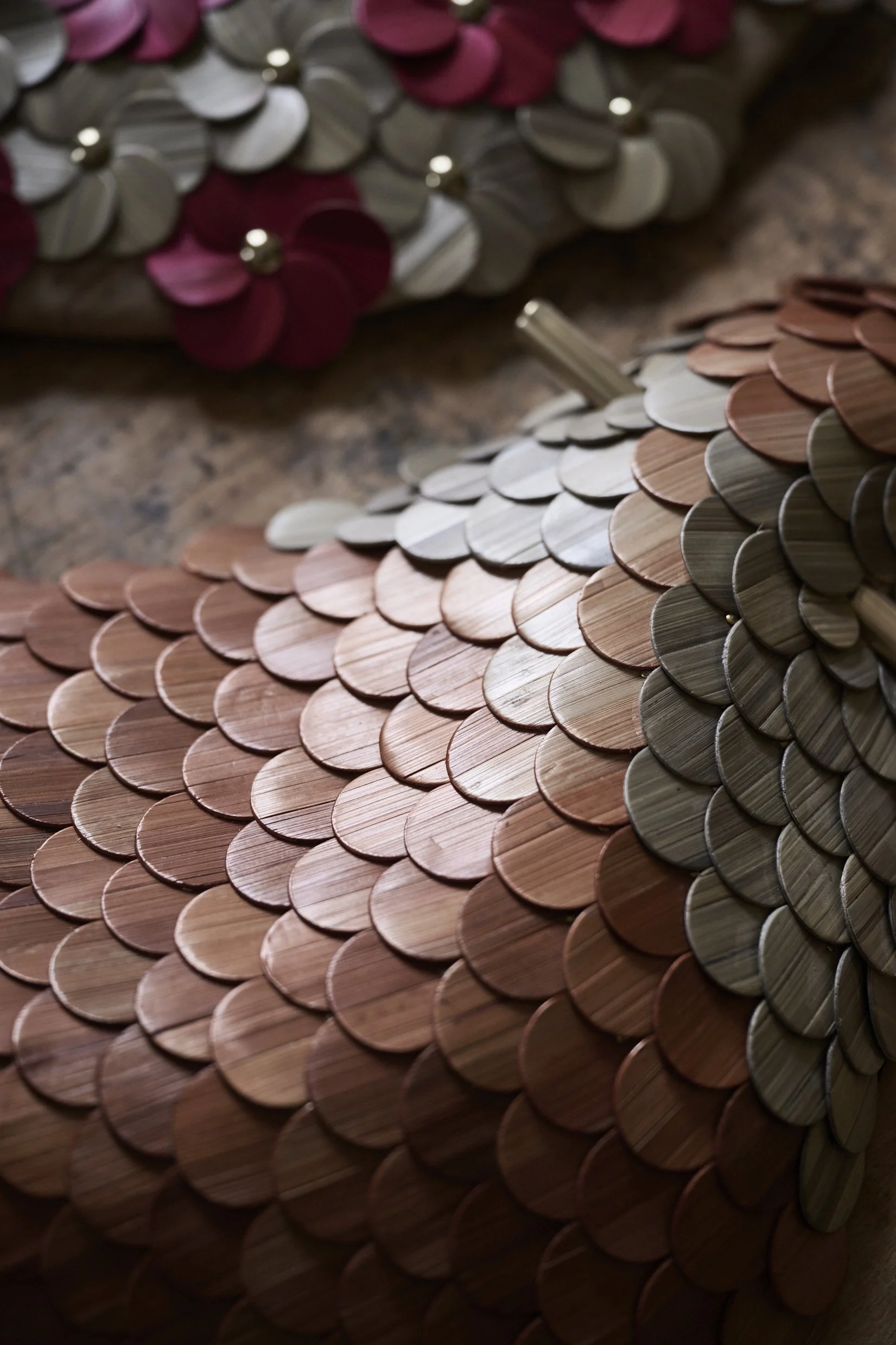 Close-up of a decorative object covered in overlapping, circular, wooden and metallic scales, arranged in a pattern.