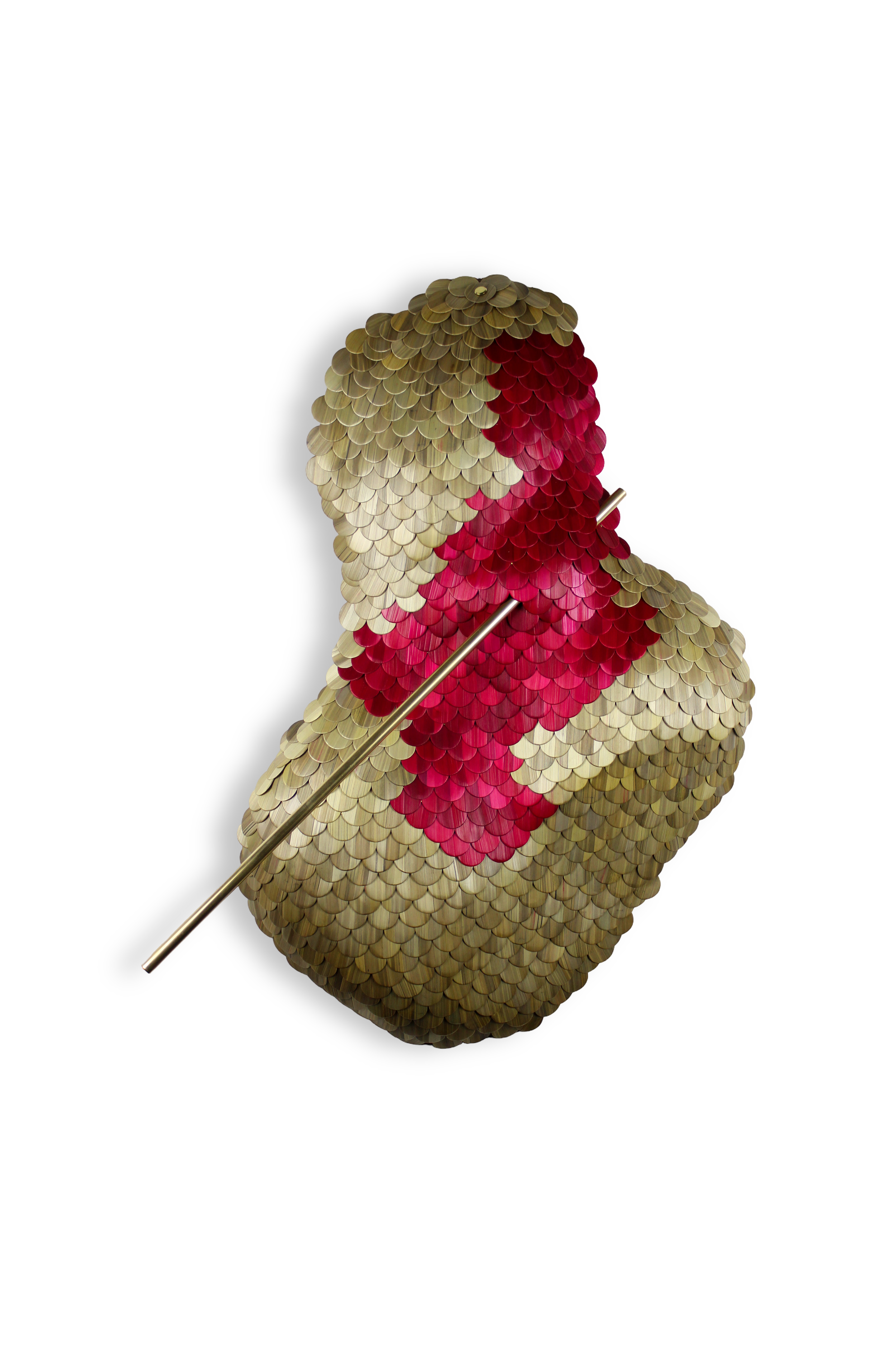 A dog sculpture made of metallic, scale-like pieces in beige and red colors, with a metallic stick through its body, set against a black background.