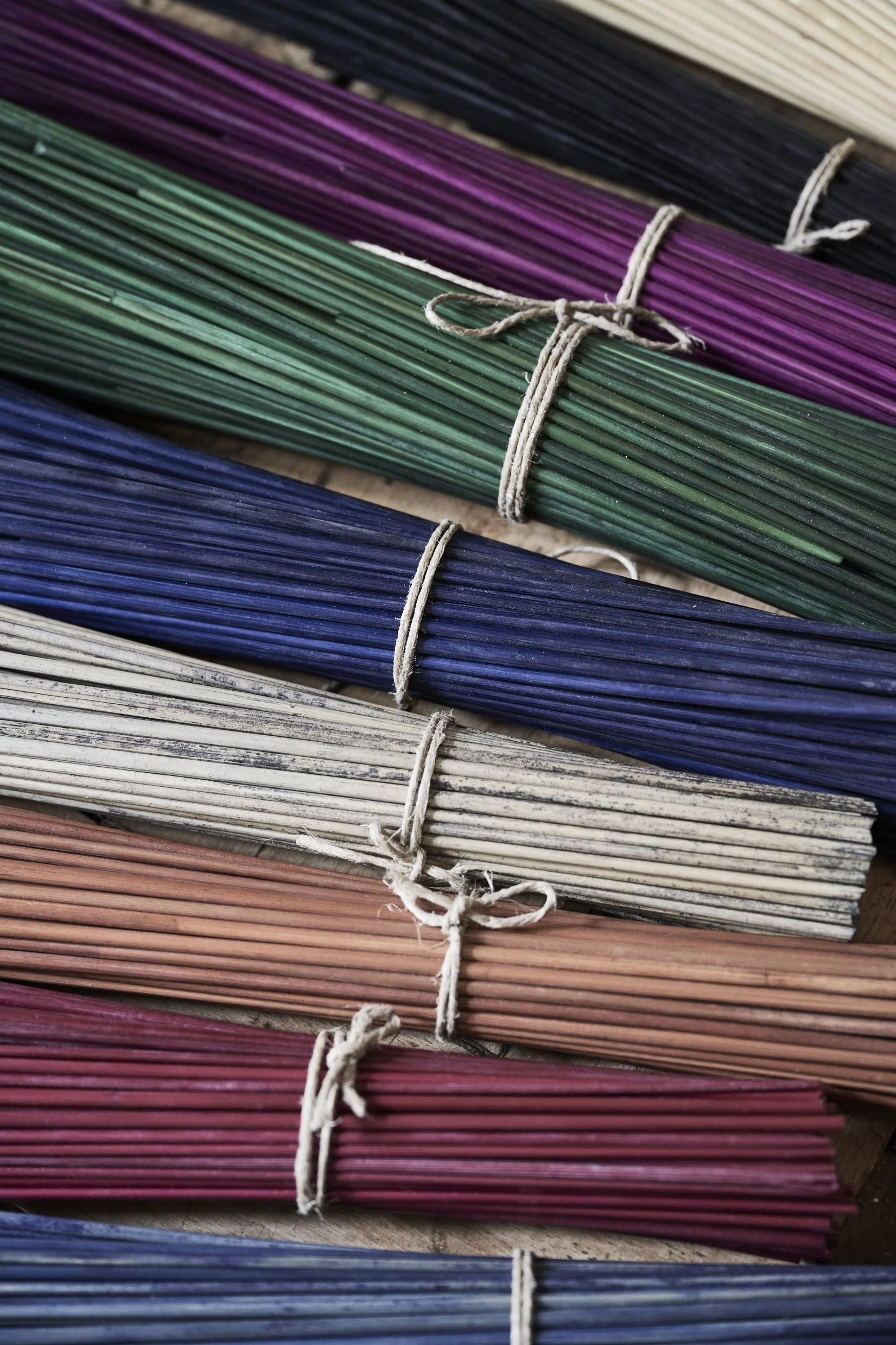 Bundles of colorful rye straw tied with strings, arranged in rows.
