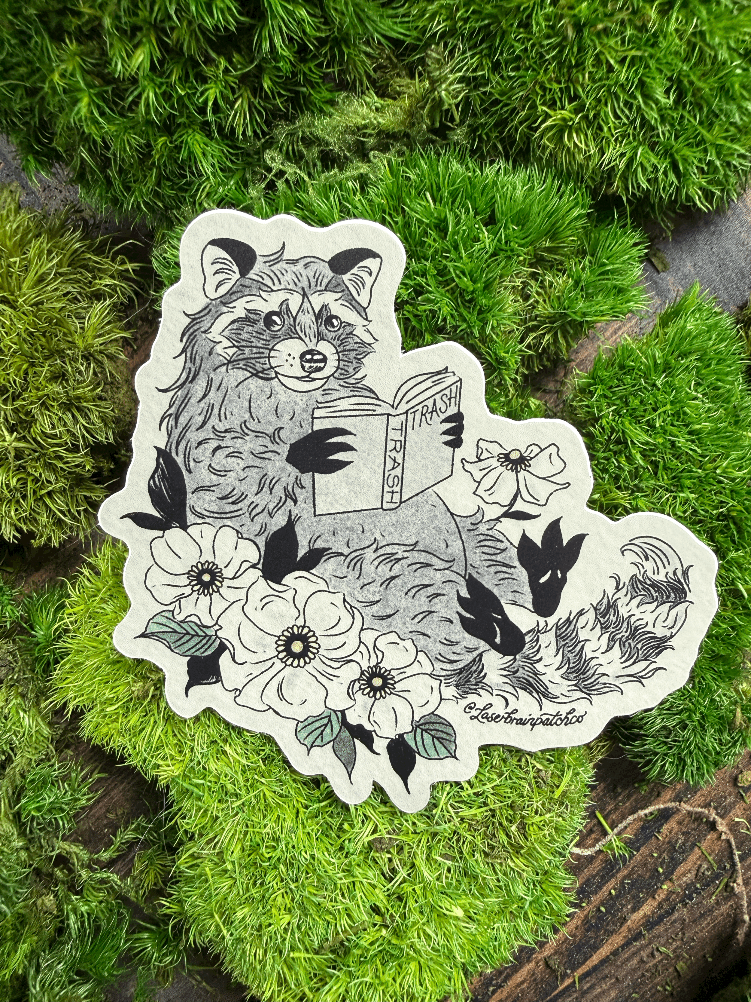 Tan Floral Lounging Trash Reading Raccoon-Sticker