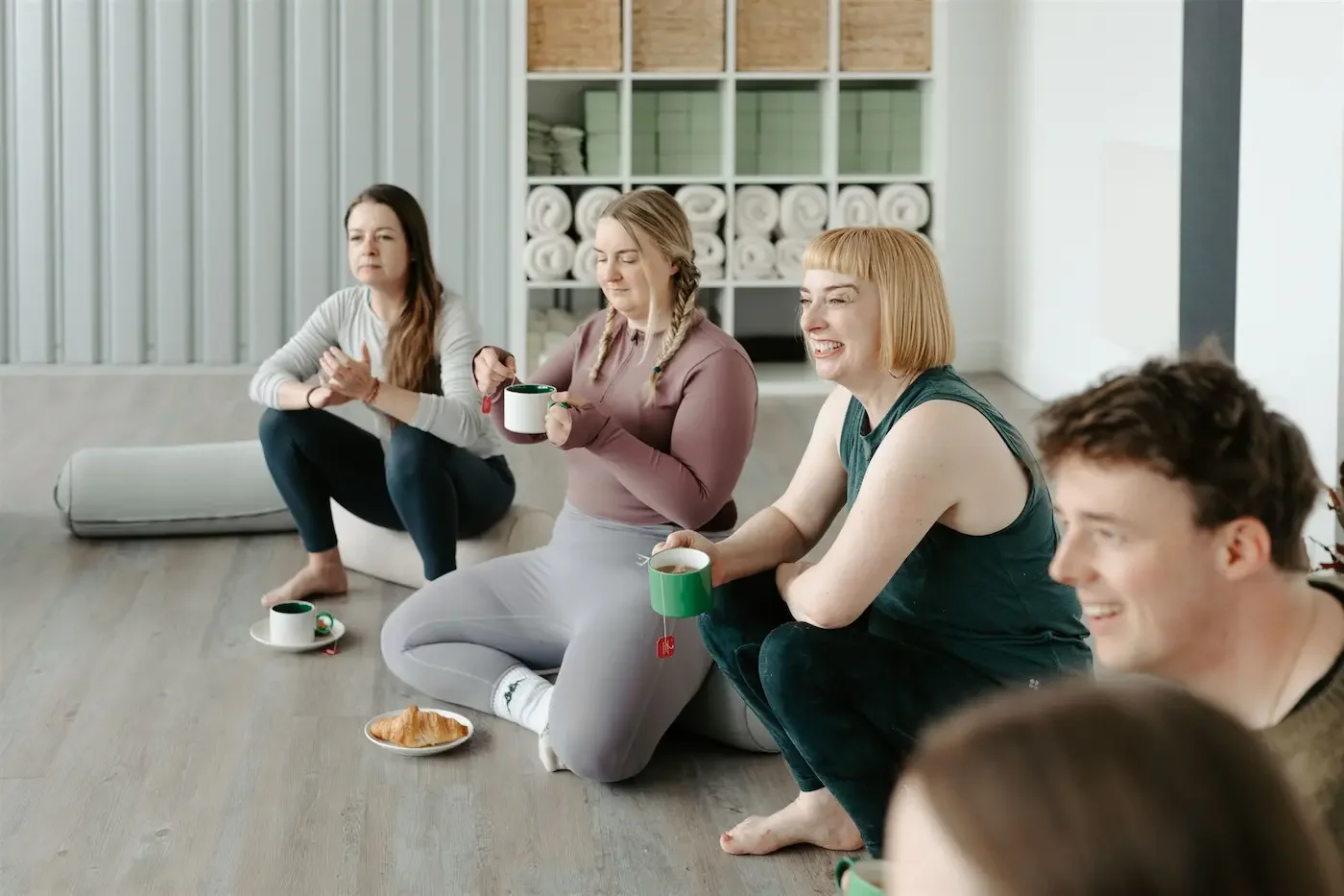 People sitting on bolsters enjoying tea and pastries after their Pilates class at Meridian Glasgow