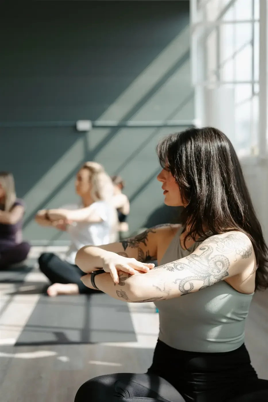 A group of people doing a seated pilates twist in the light filled studio at Meridian in Glasgow