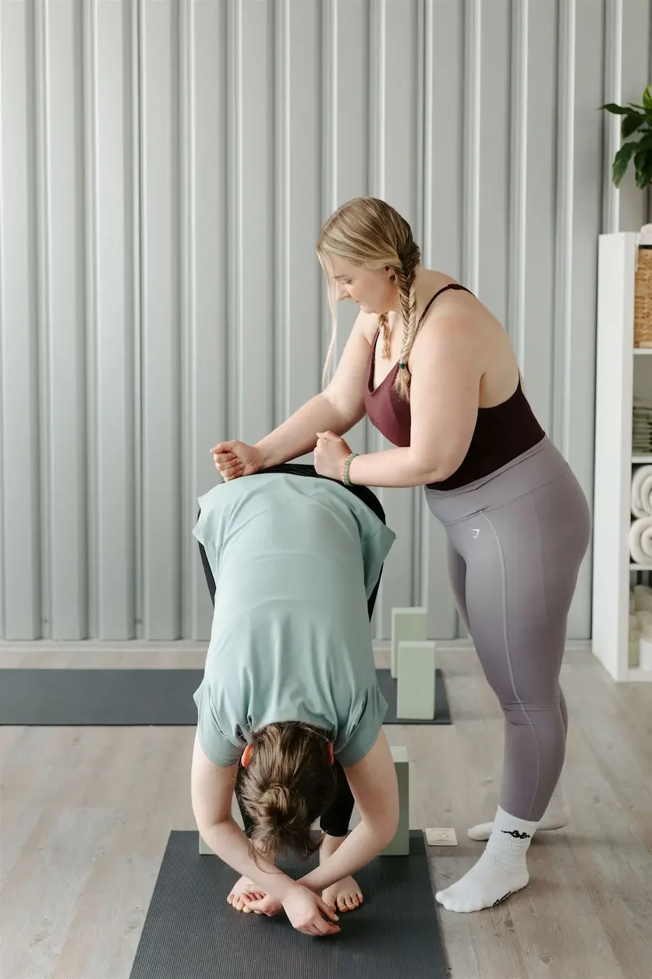 Close-up of a student in downward dog receiving a supportive adjustment during a private yoga session at our Glasgow East End studio