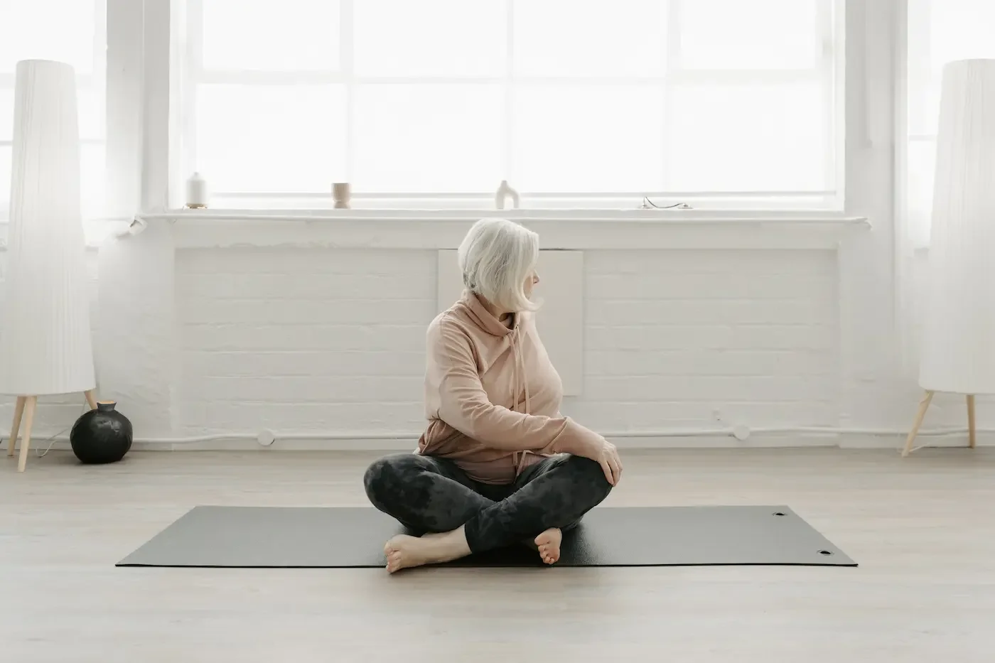 woman practicing a seated yoga twist during a class in the bright main studio at our Glasgow East End yoga and Pilates studio