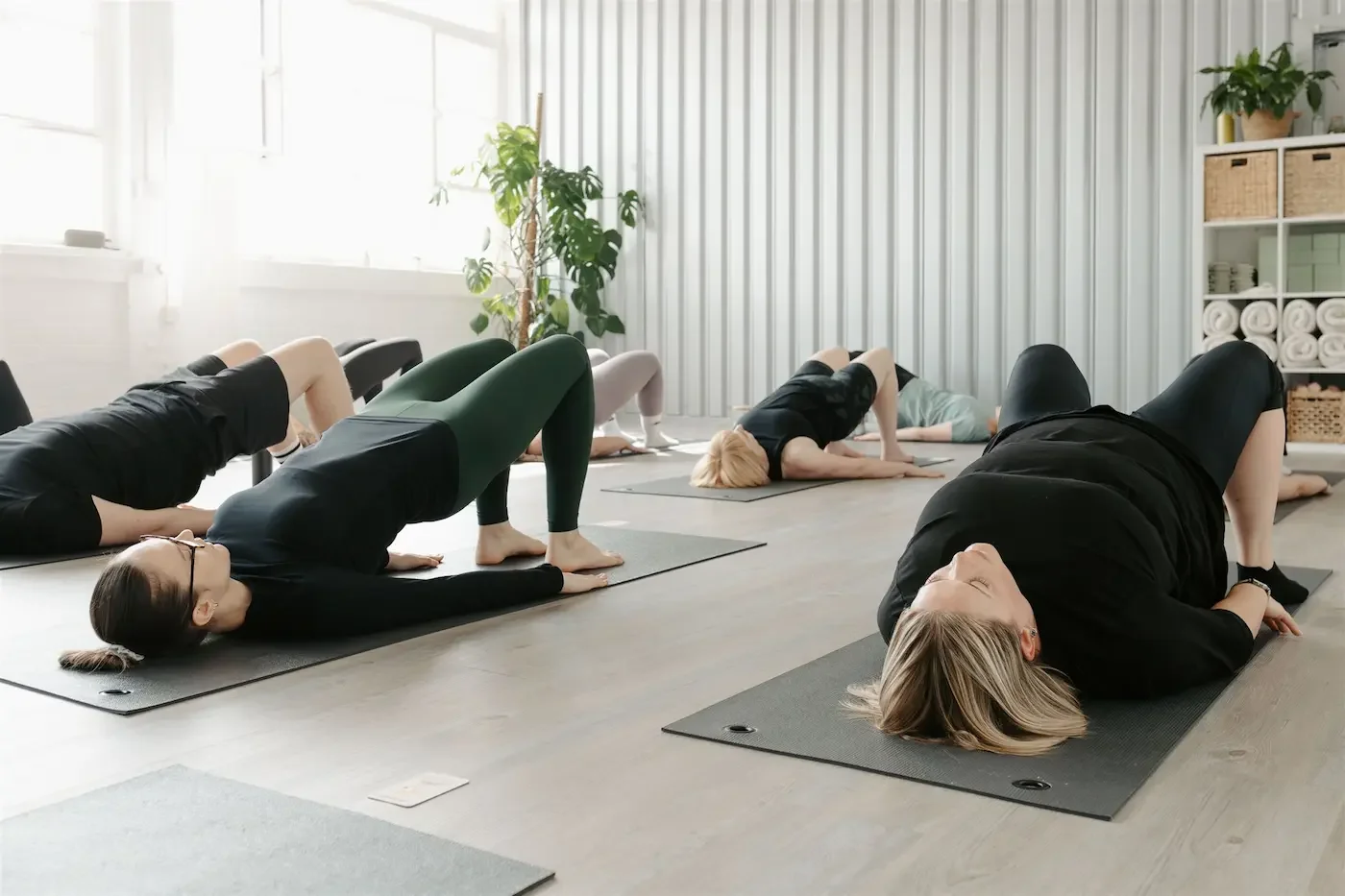 Students performing shoulder bridge Pilates in a light-filled, minimalist studio at our Glasgow East End yoga and Pilates studio