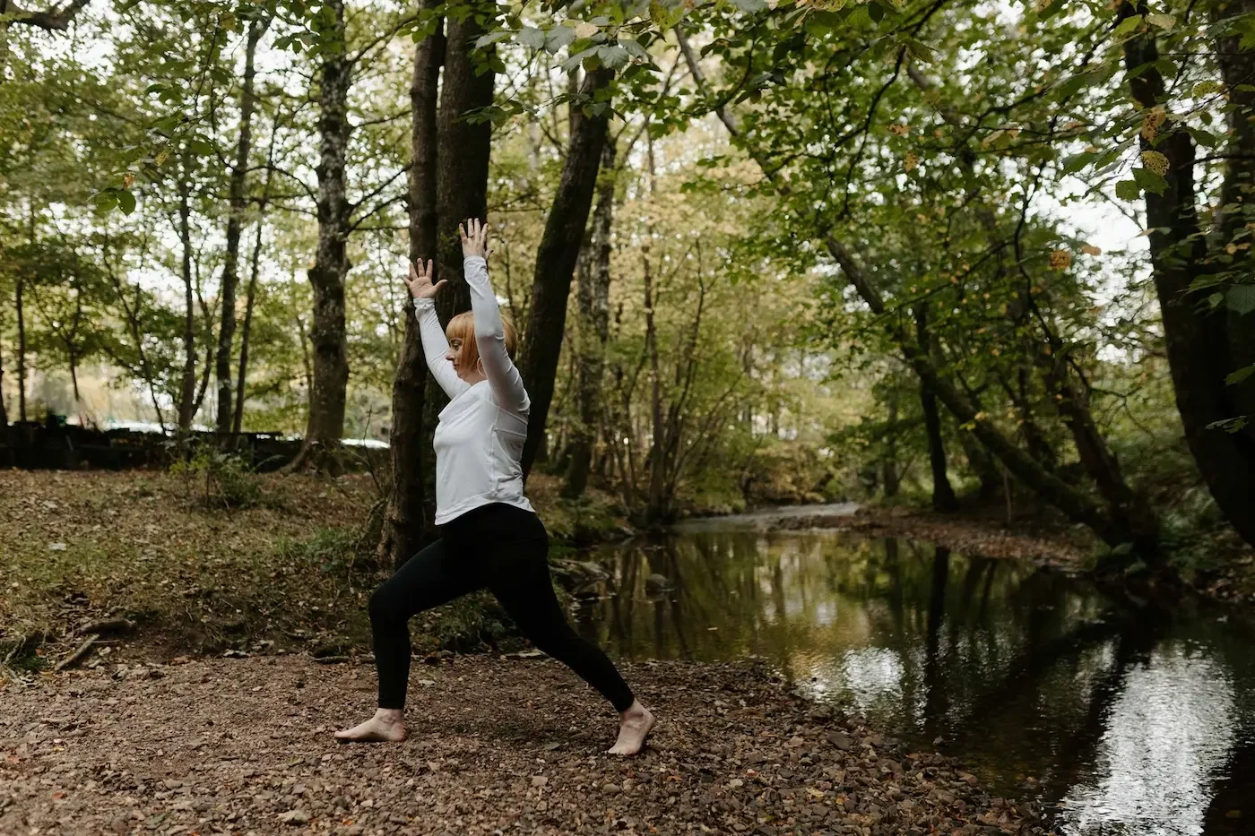 Michelle Lang, 200-hour yoga teacher training, demonstrating a high lunge pose in a peaceful woodland setting near the East End of Glasgow.