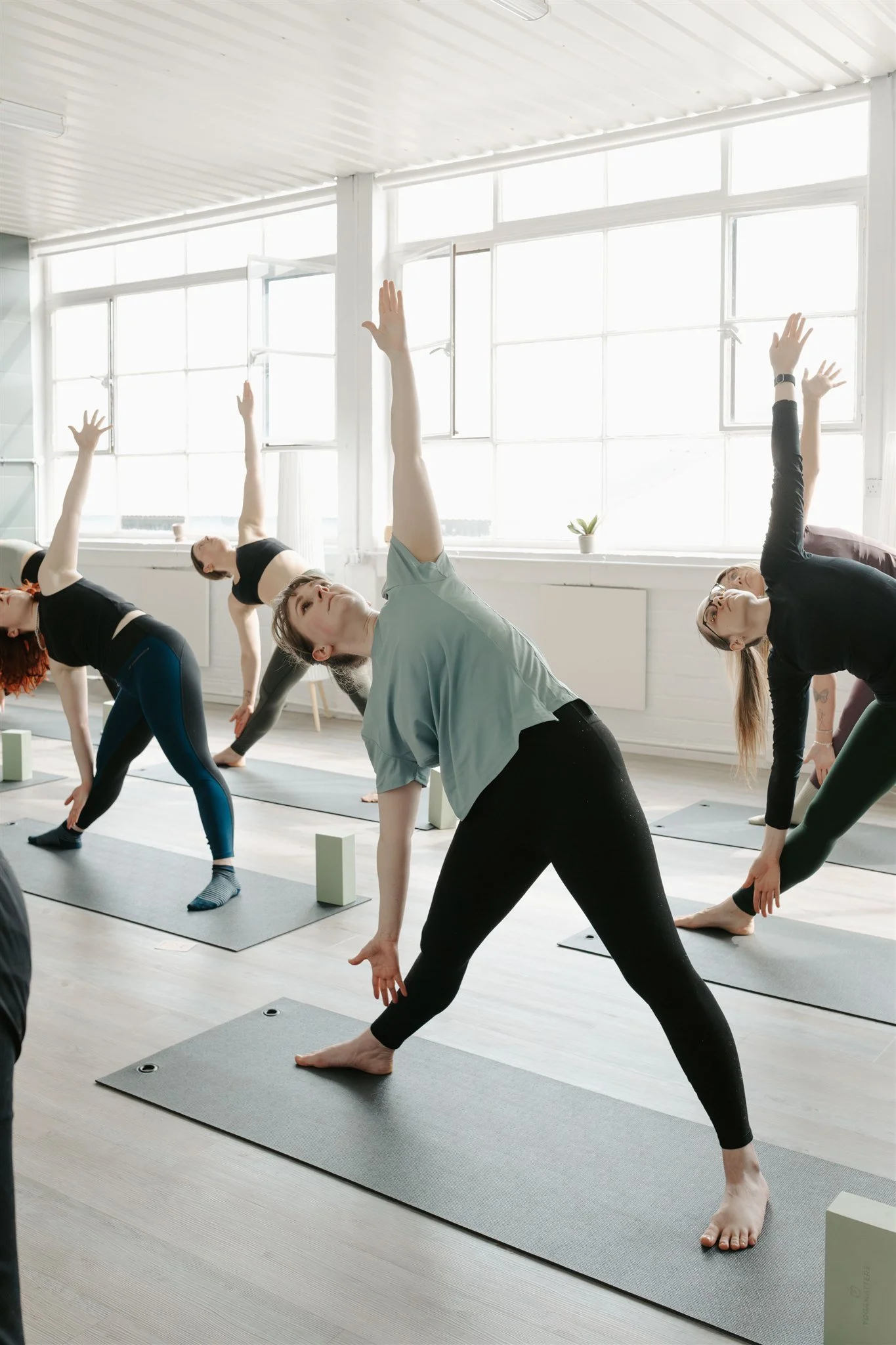 A group practicing slow flow vinyasa at meridian yoga and pilates glasgow in a light filled studio
