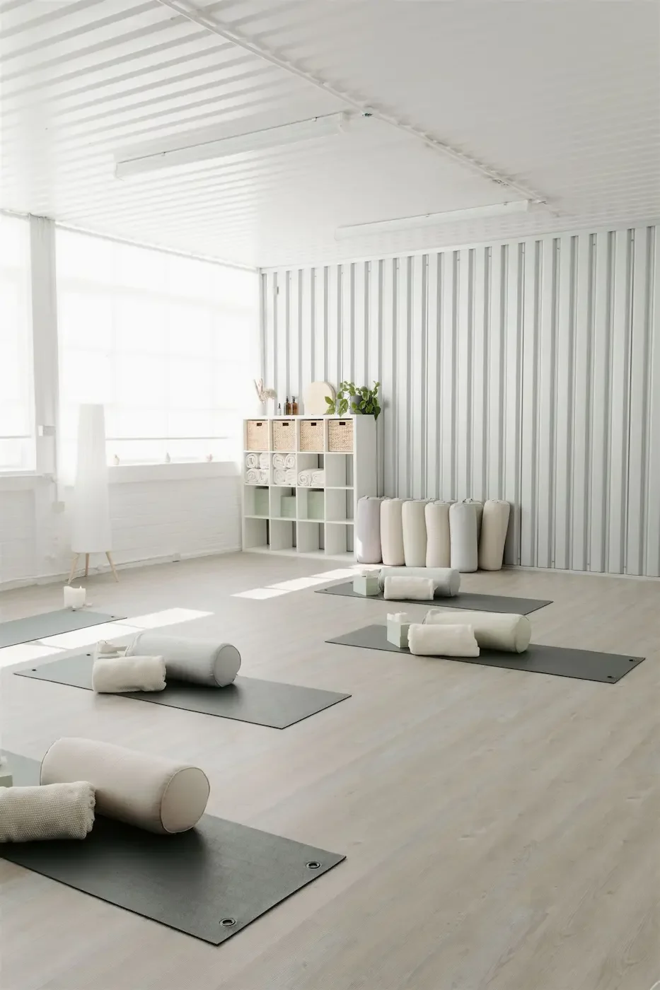 A bright, minimalist yoga studio with neatly arranged mats, bolsters, and natural light streaming through large windows at Meridian Glasgow.
