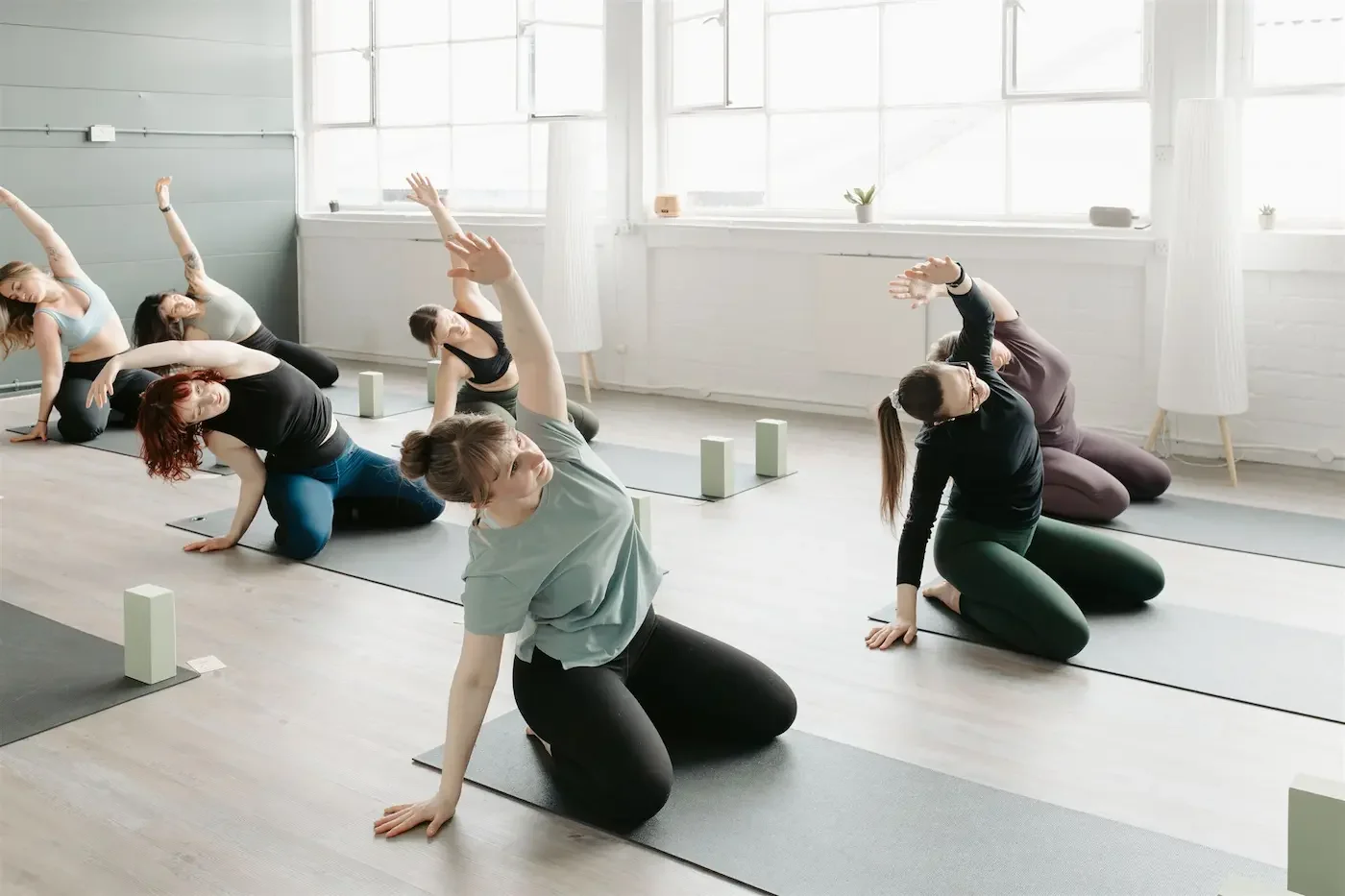 Group practicing gentle side stretches during a Beginners Yoga class at Meridian Yoga & Pilates in Glasgow’s East End
