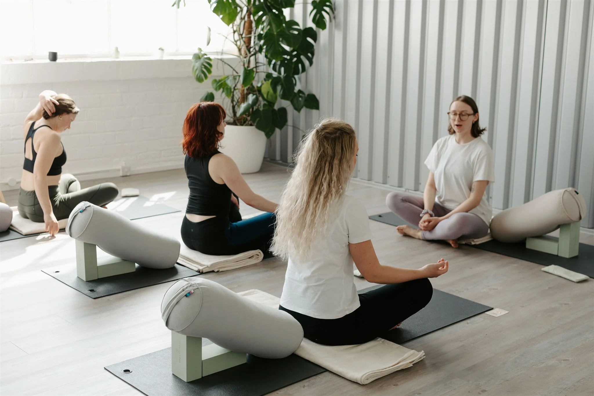  A group of people being guded through a gentle yoga practice in a bright and airy studio