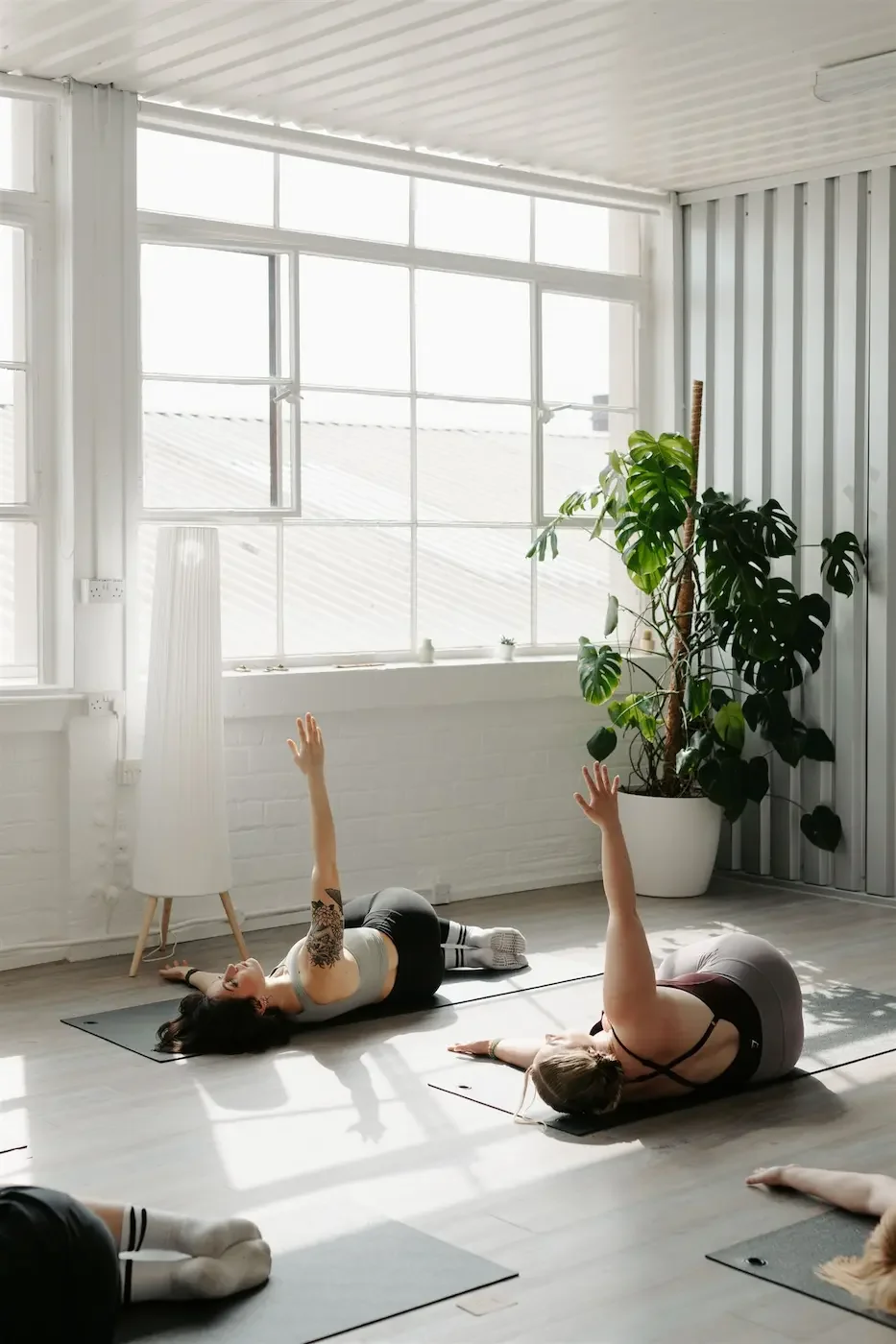 Group preparing to practice a yoga twist in a bright, light-filled studio at Meridian Yoga & Pilates in Glasgow’s East End