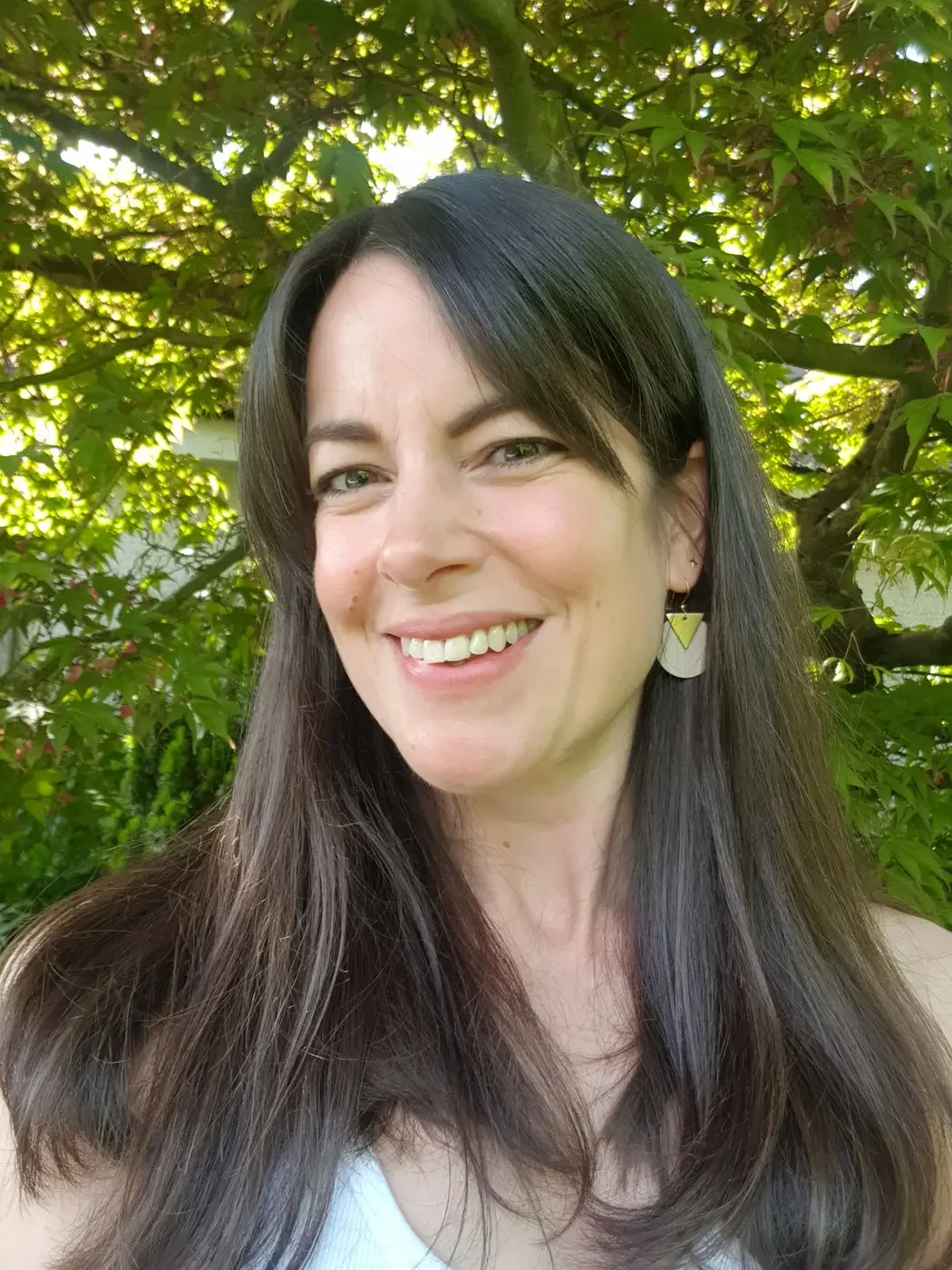 Portrait of Rebecca Redpath, Pilates Teacher at Meridian Yoga & Pilates, smiling outdoors beside trees