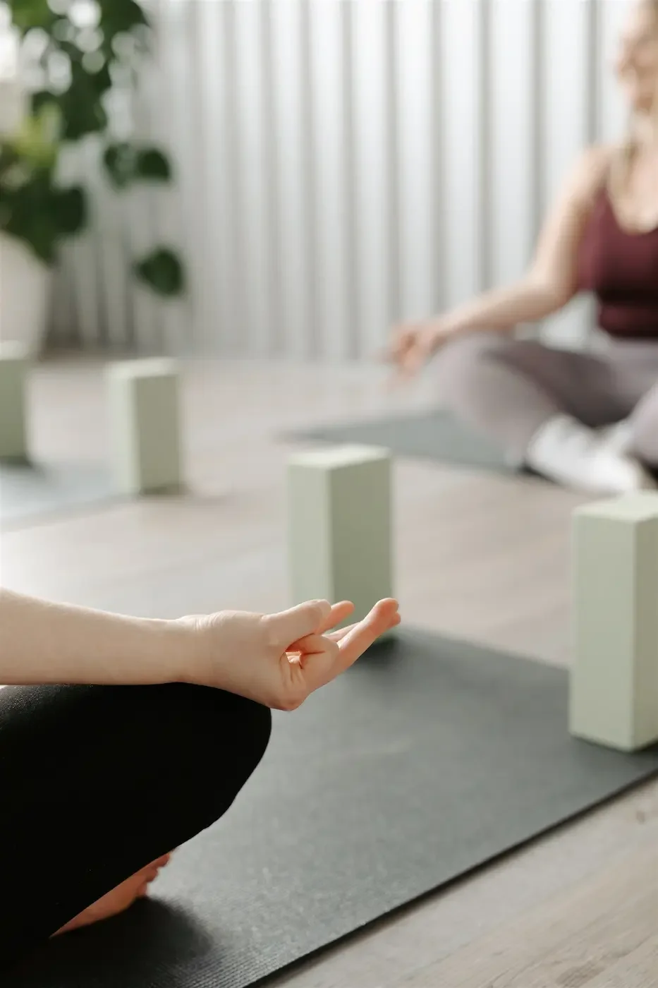 Someone sitting cross legged in the studio at Meridian with their hands in a mudra