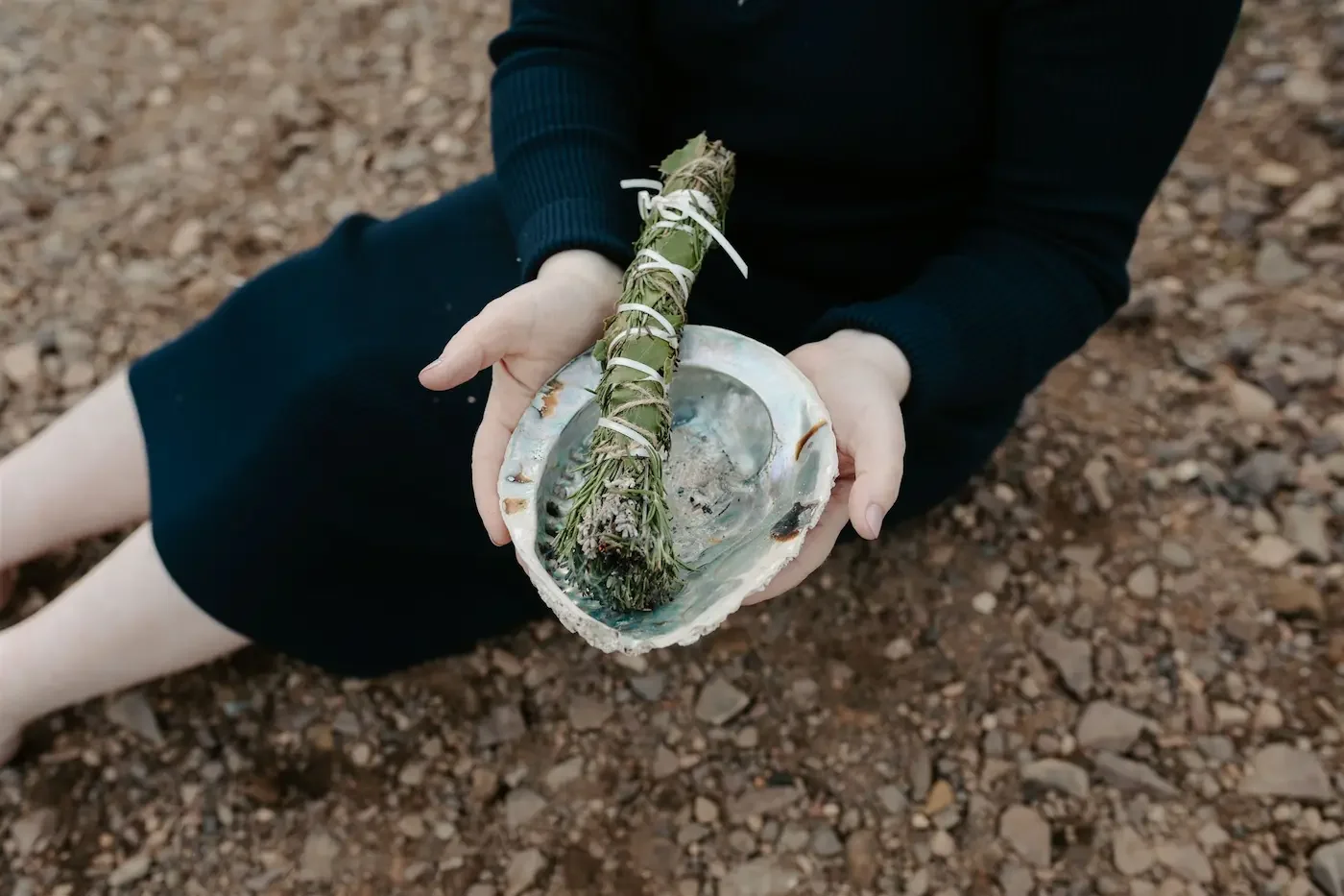 Michelle Lang, Shamanic Practitioner, holding up a large shell containing sage during a ritual outdoors near Glasgow.