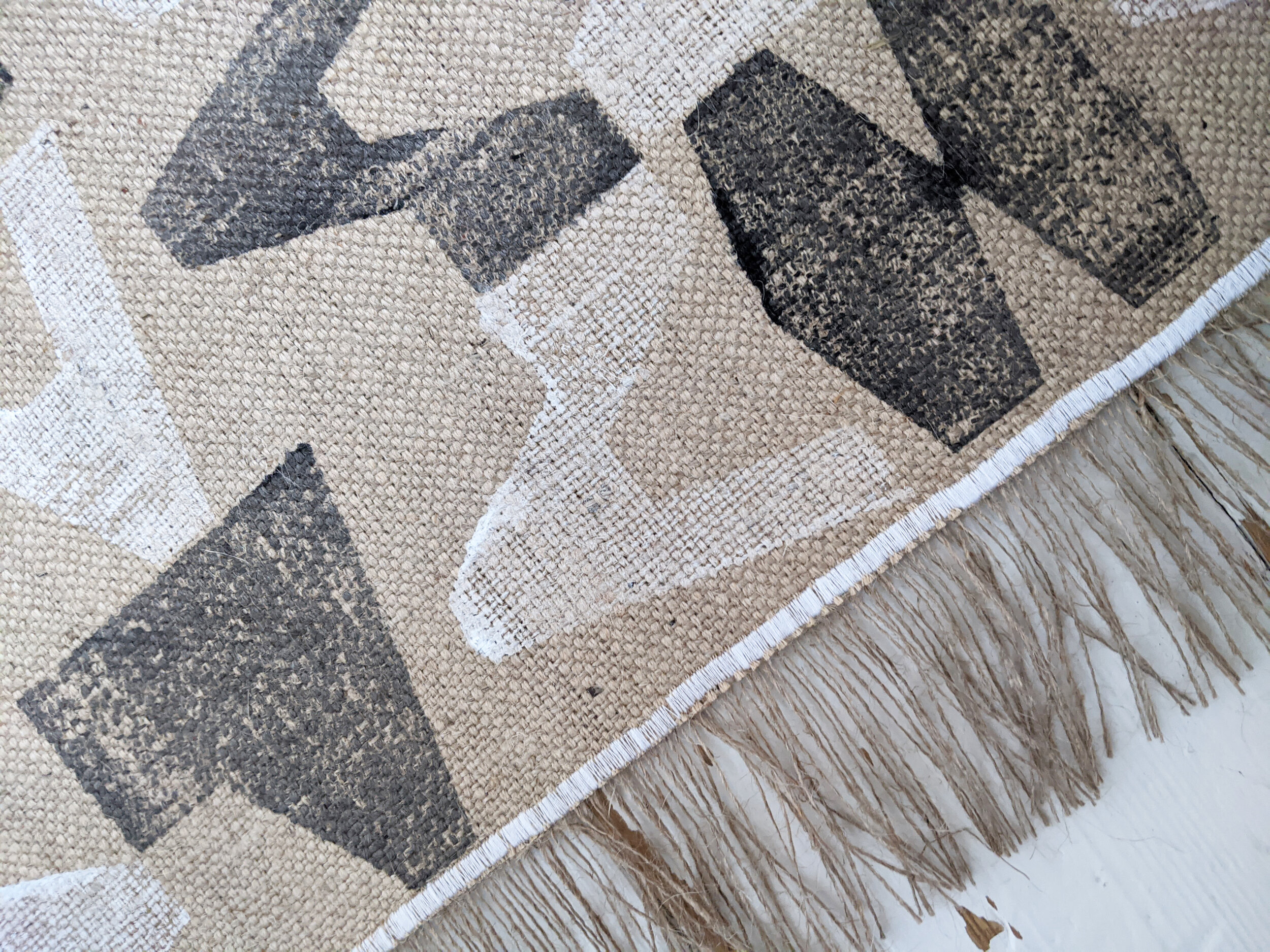 detail of modern block printed jute rug with fringe
