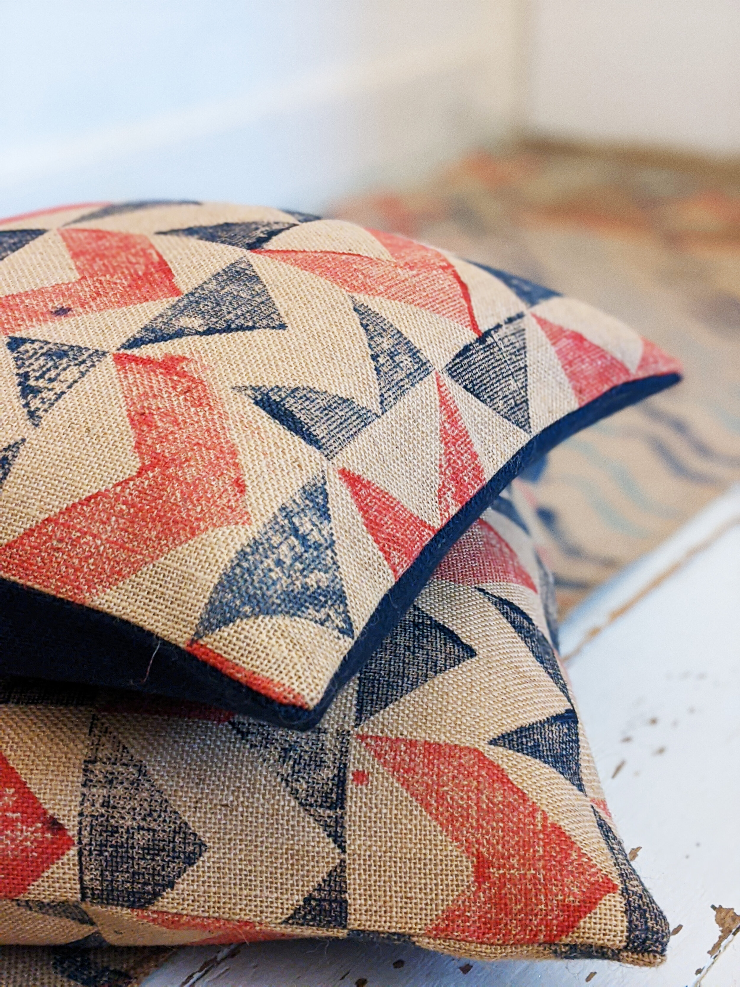 SOROMPÓ industrial inspired jute cushion with chevron design and nautical colours on floor with rug