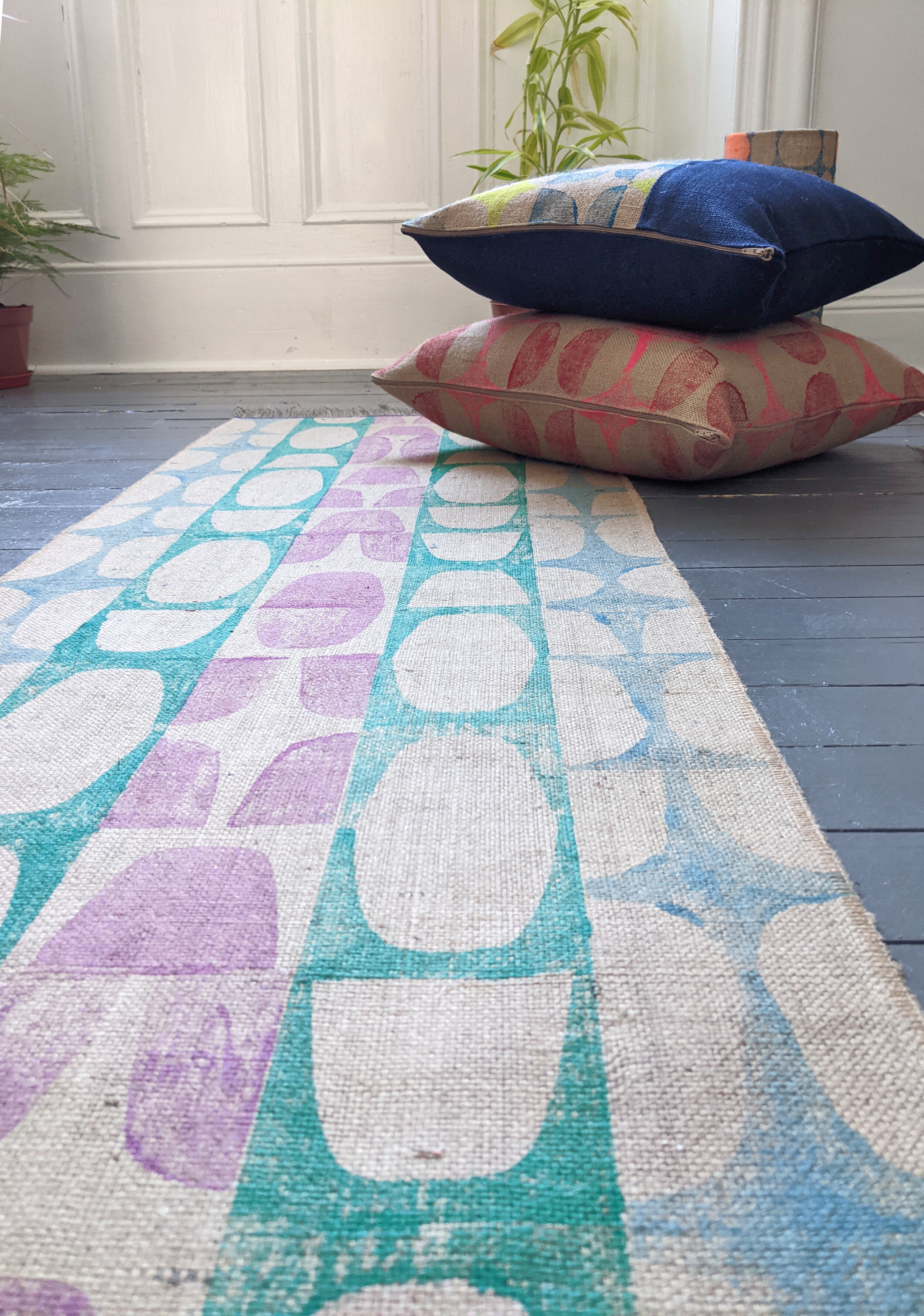interior scene with retro inspired modernist print on runner rug with cushions and houseplant on wooden floor