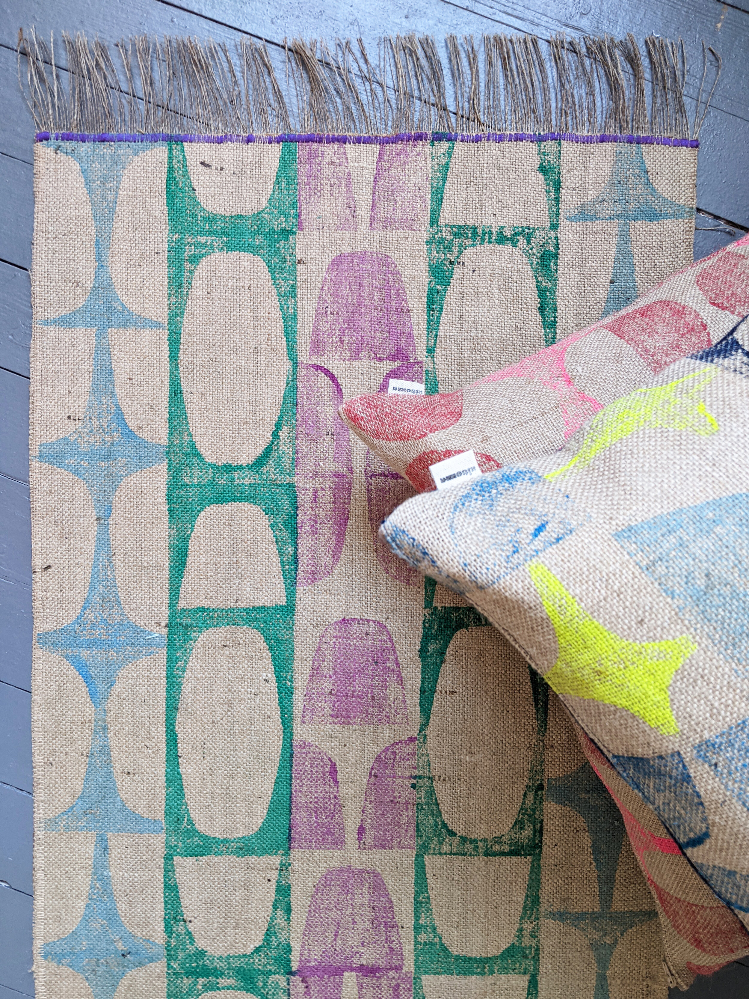 colourful runner rug with modernist retro block print and cushions on wooden floor