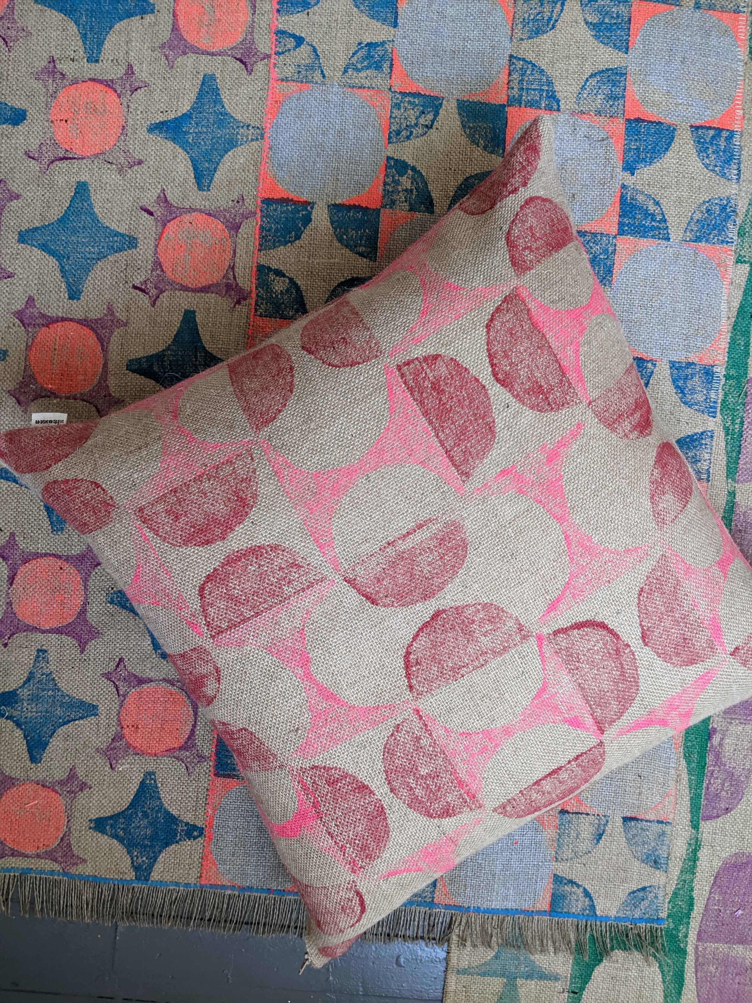 interior scene with cushion in 1960s abstract geometric pattern laid on hand block printed jute rugs