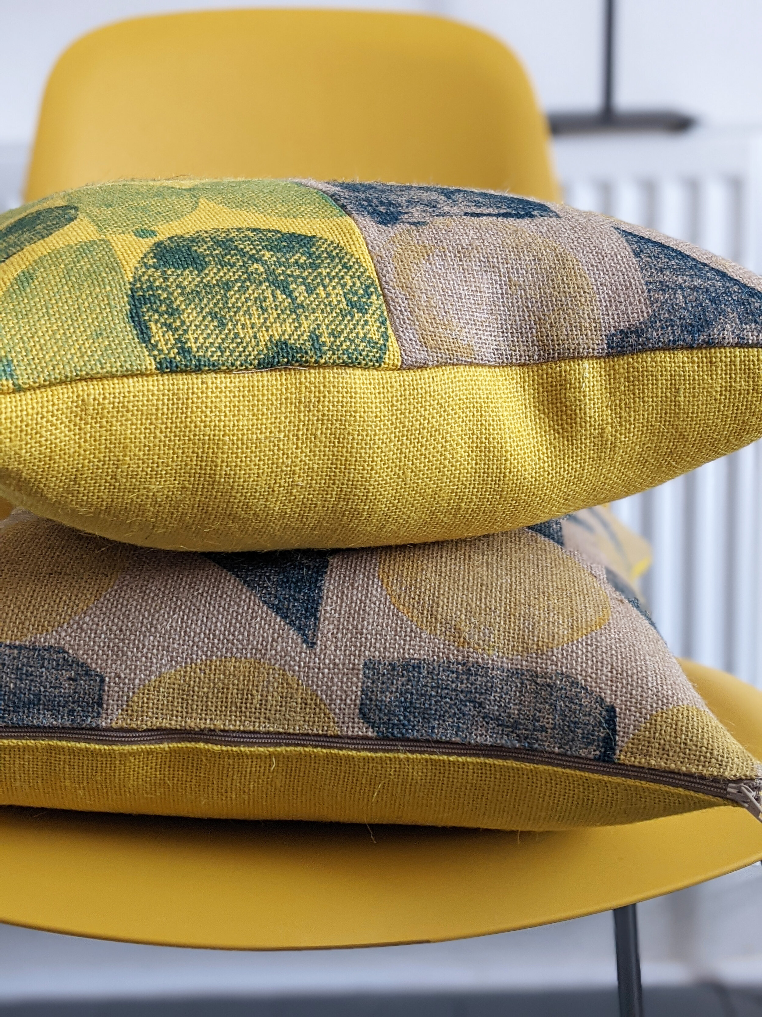 modern interior with yellow chair and geometric printed cushions stacked