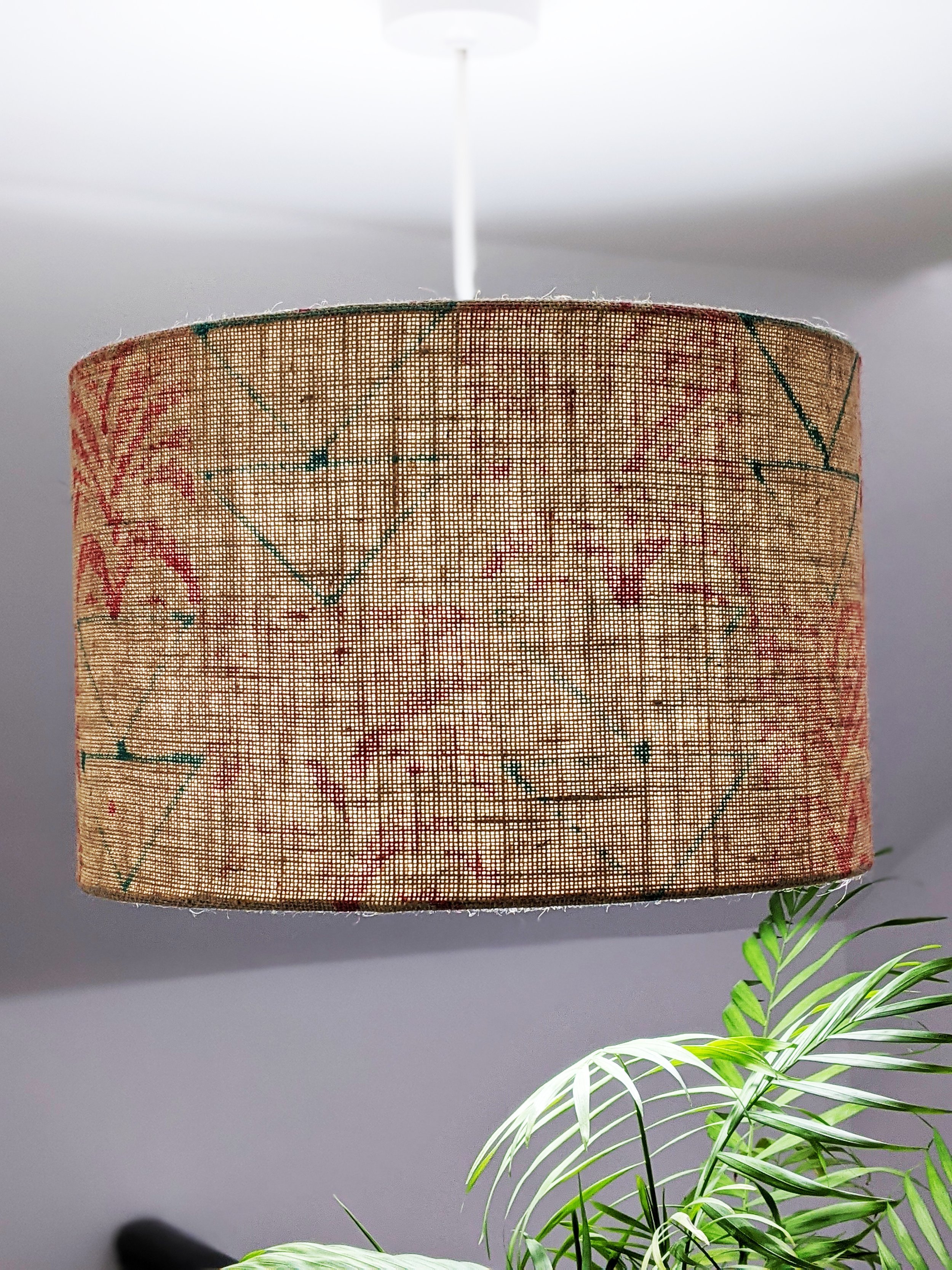 large lampshade hanging from ceiling with light on, illuminating natural jute texture