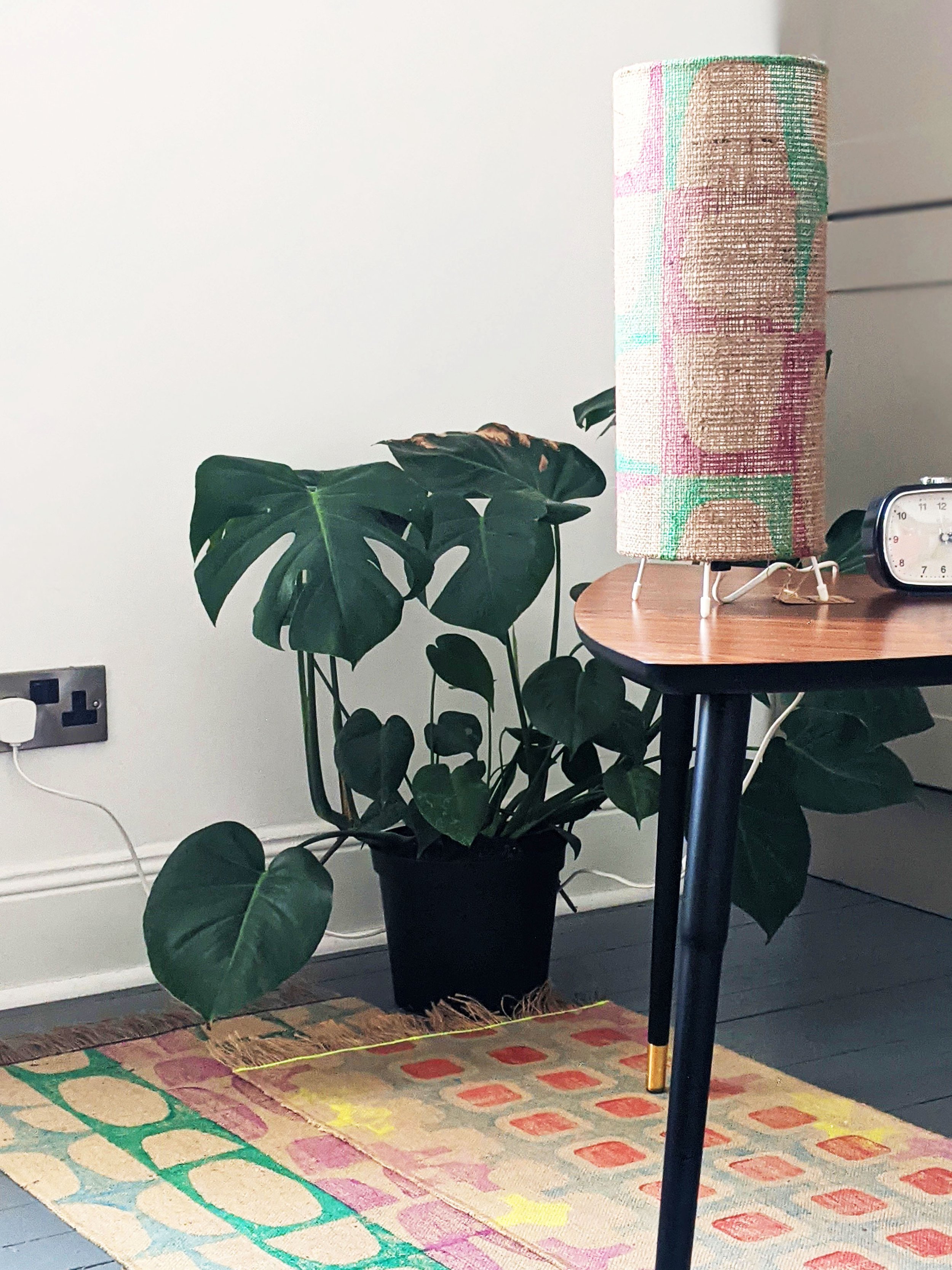 retro interior scene with floor lamp on side table and colourful printed jute rugs