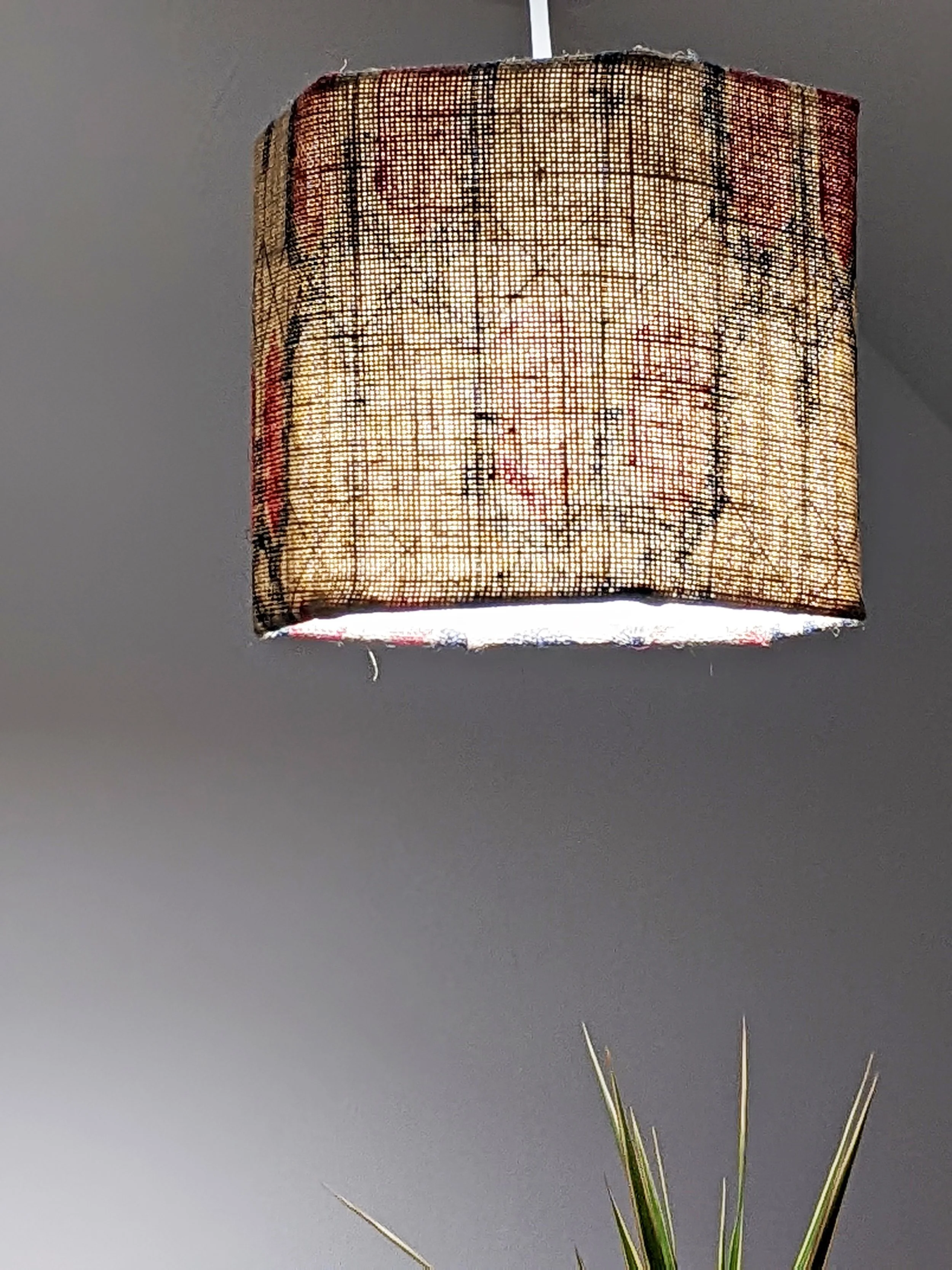 small hexagonal lampshade hanging from ceiling lit up in geometric block printed pattern in nautical colourways