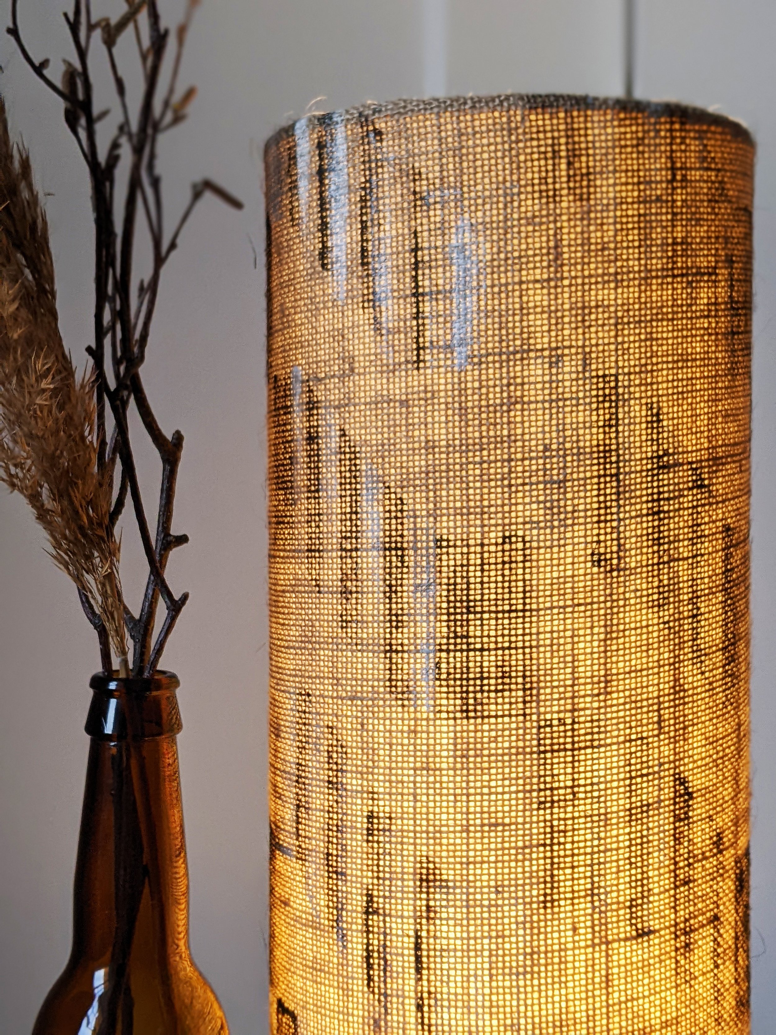 illuminated detail of natural jute lamp with brutalist geometric architectural print