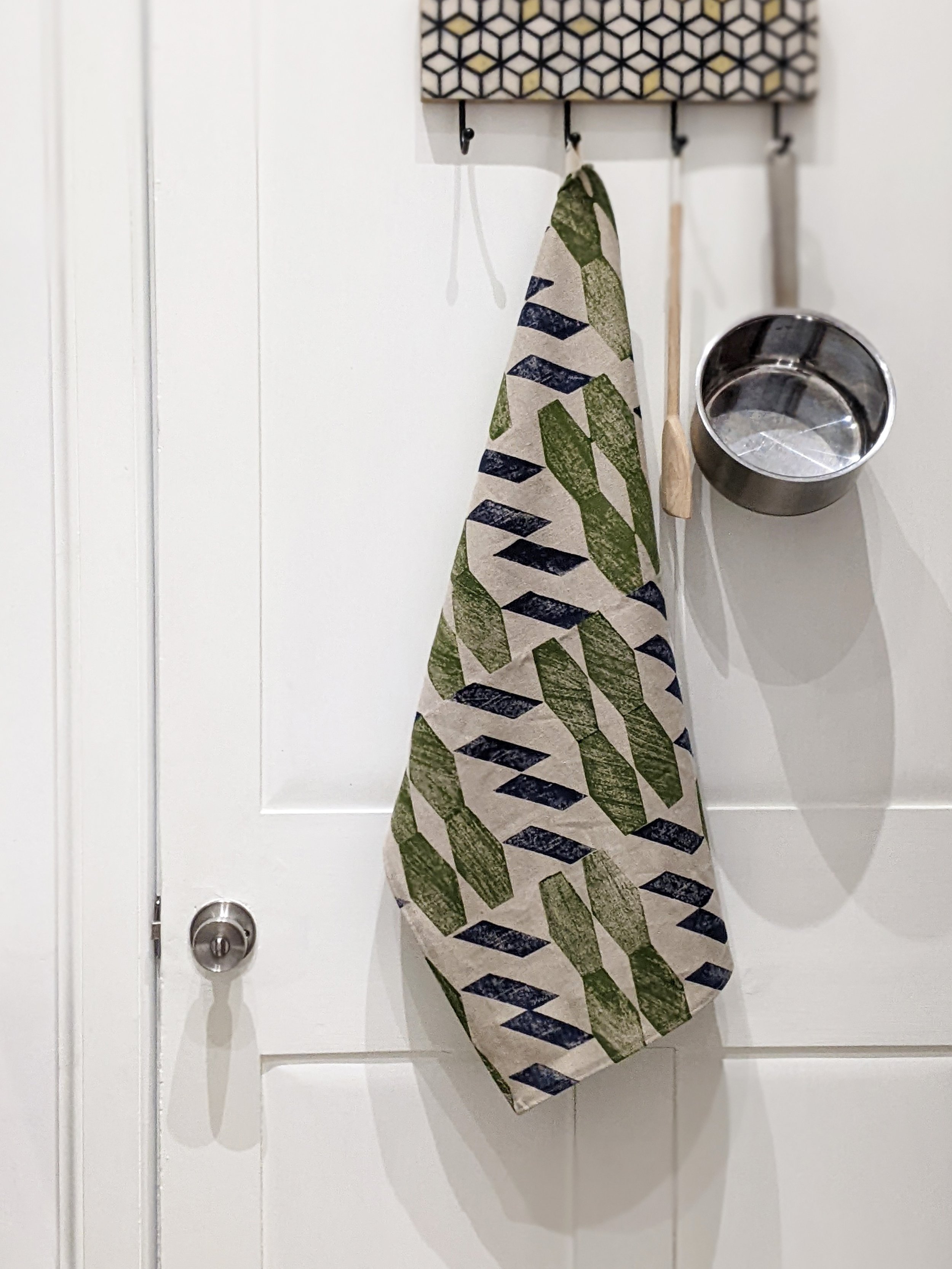 large hand printed geometric teatowel hanging on hook in kitchen