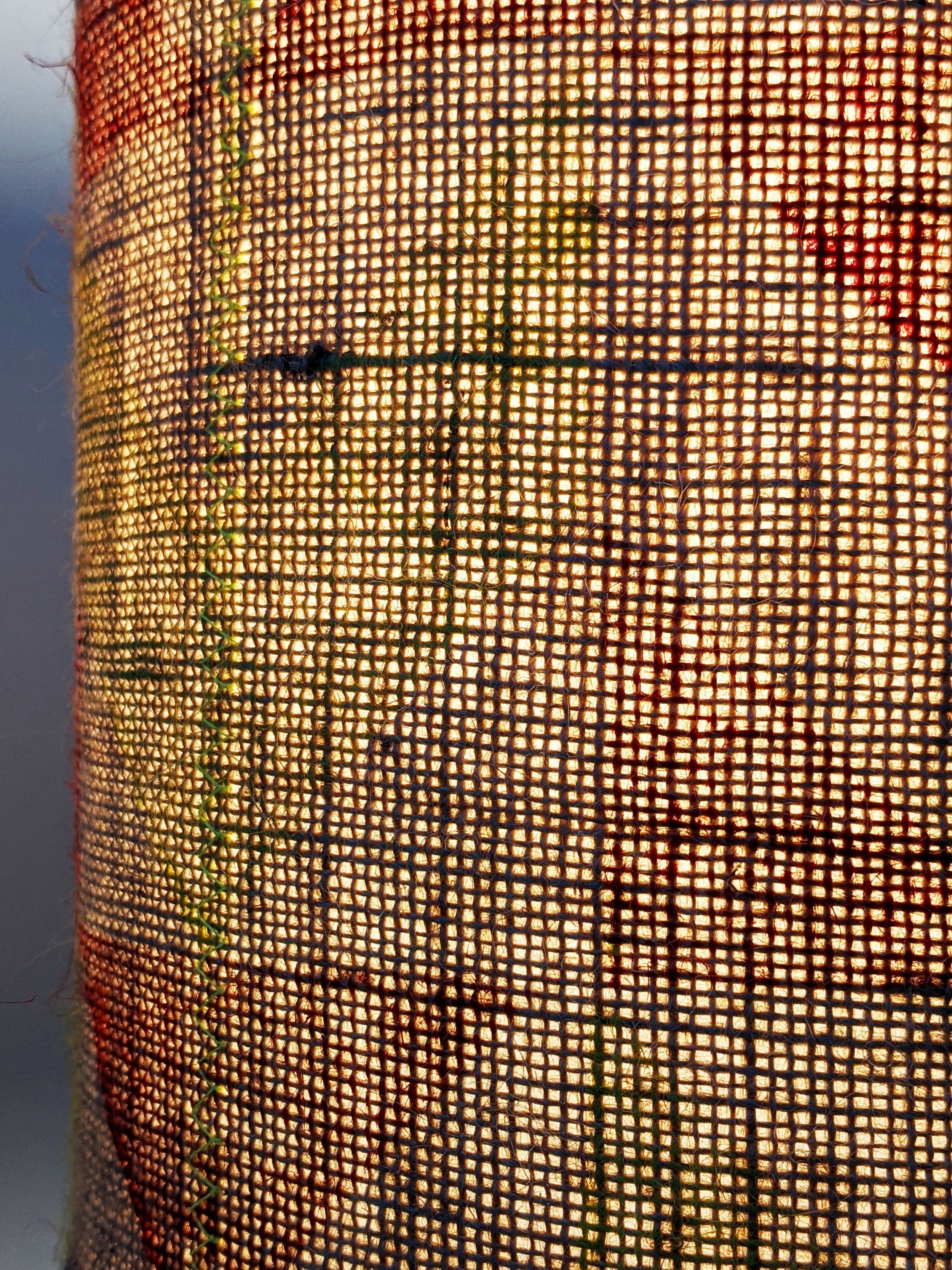 close-up detail of stitched pattern on printed jute texture on lampshade with light on