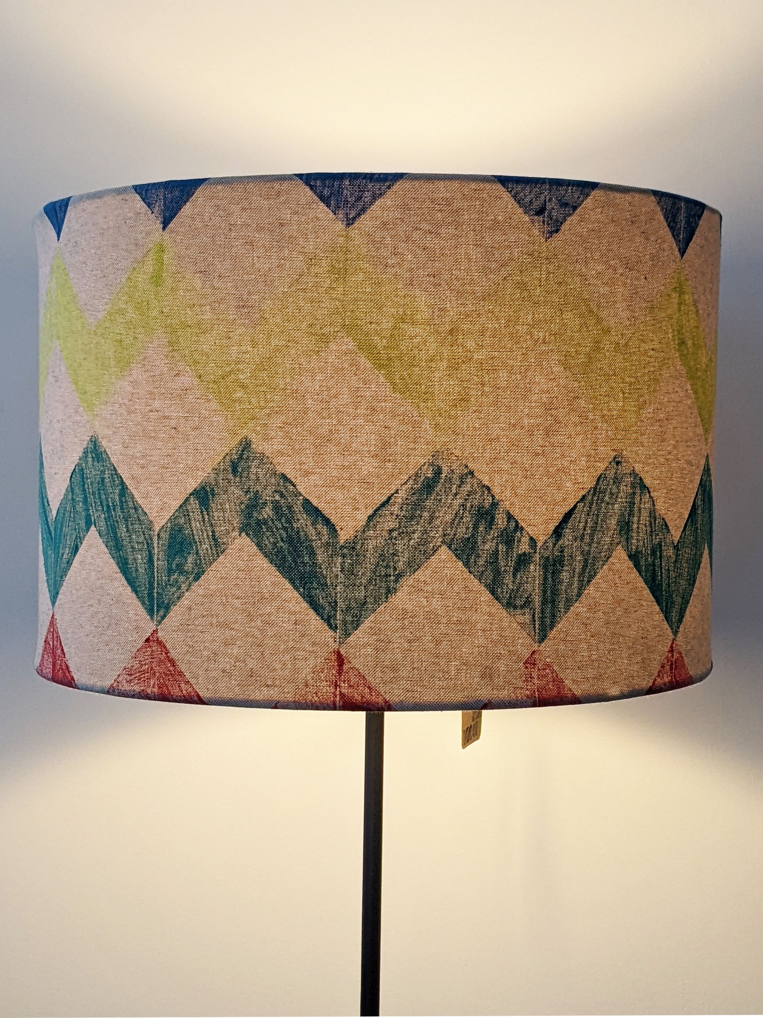 large drum lampshade with colourful geometric pattern with light on