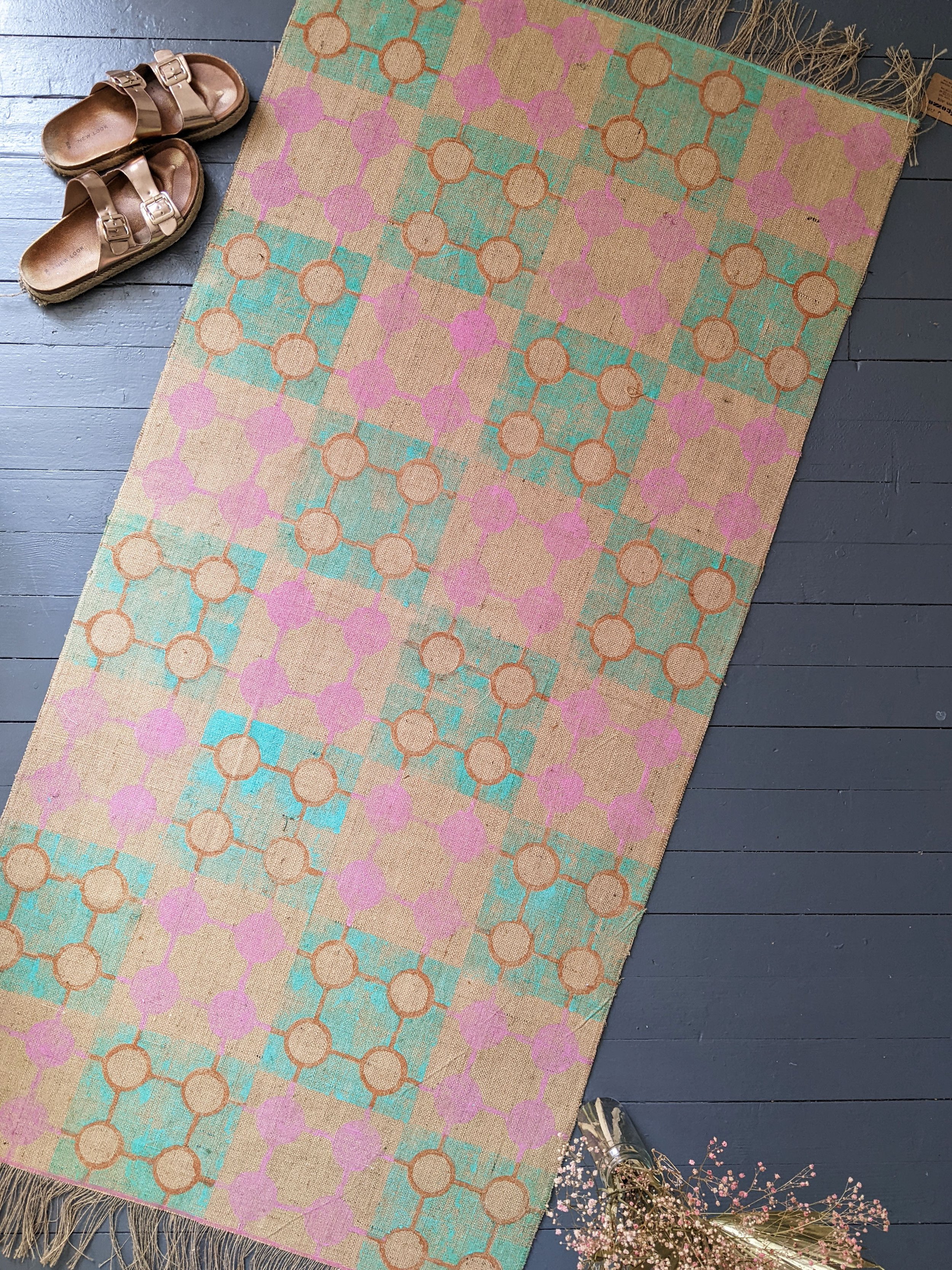hand block printed, geometric rug with pastel colours on floor with shoes and flowers
