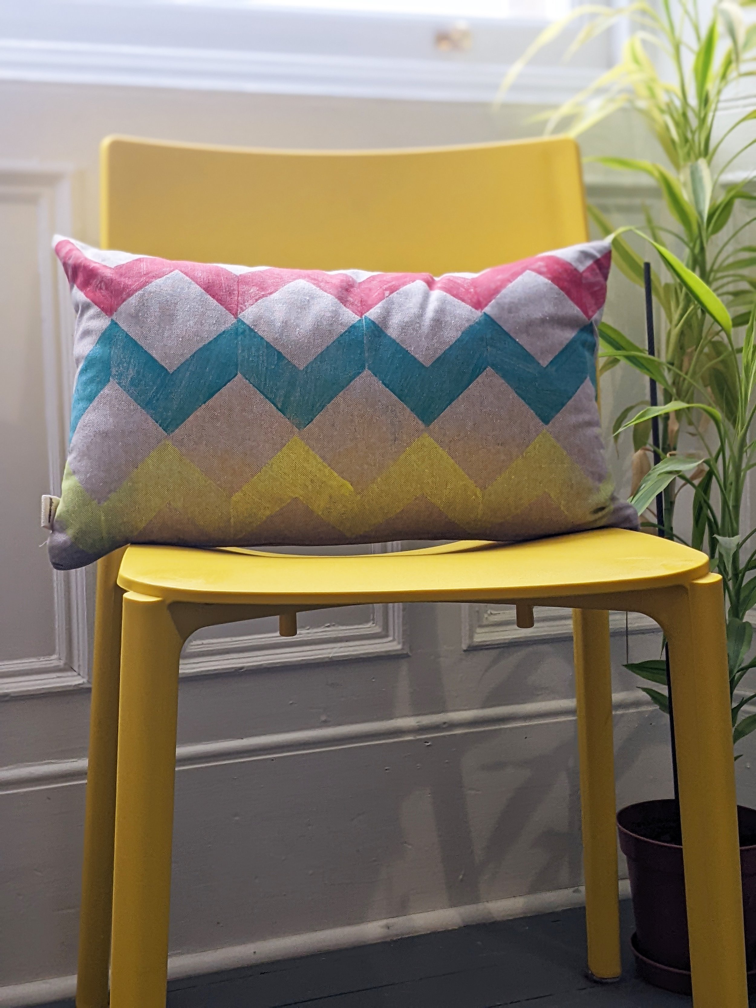 interior scene with rectangular cushion in bold colour zigzag print on yellow chair