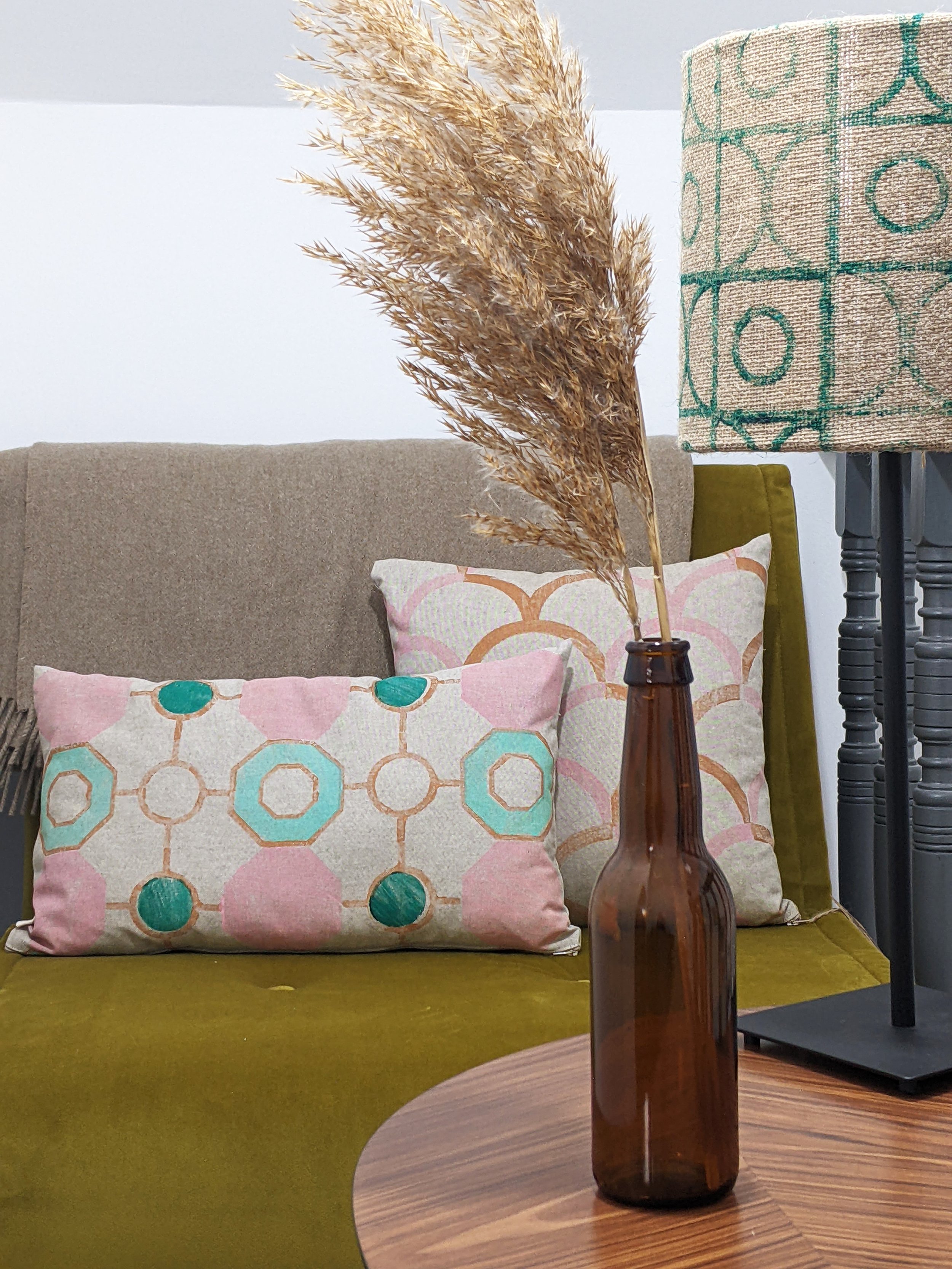 boho vintage deco inspired interior scene with pastel printed cushions and green jute lampshade