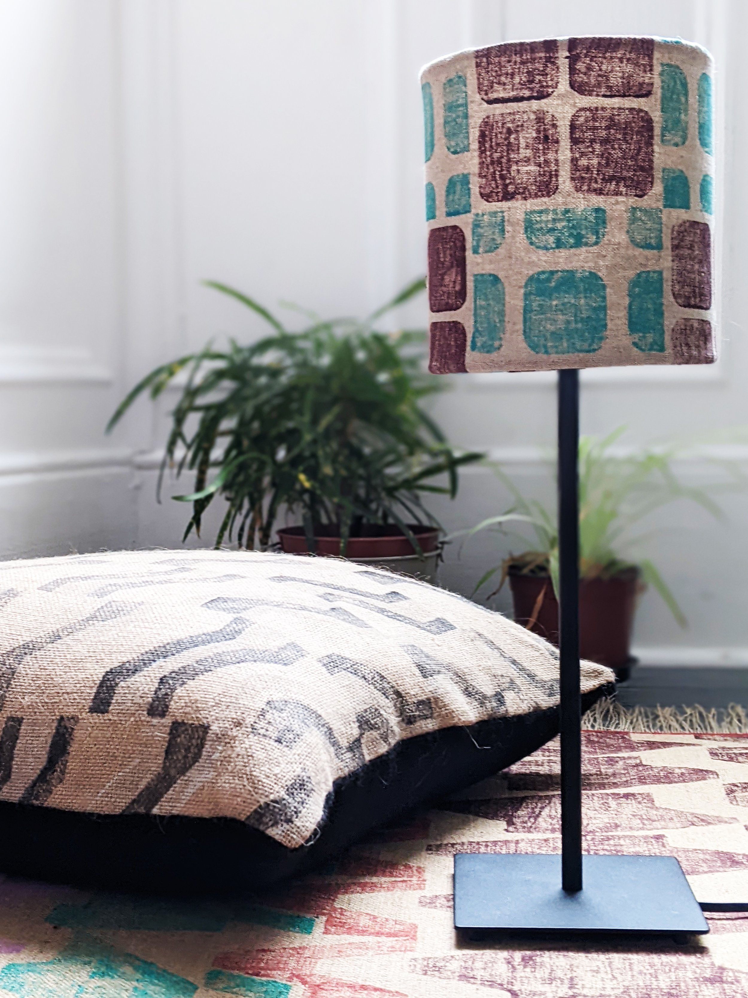 contemporary interior scene with small geometric lampshade on floor with brutalist, architectural rug and cushion
